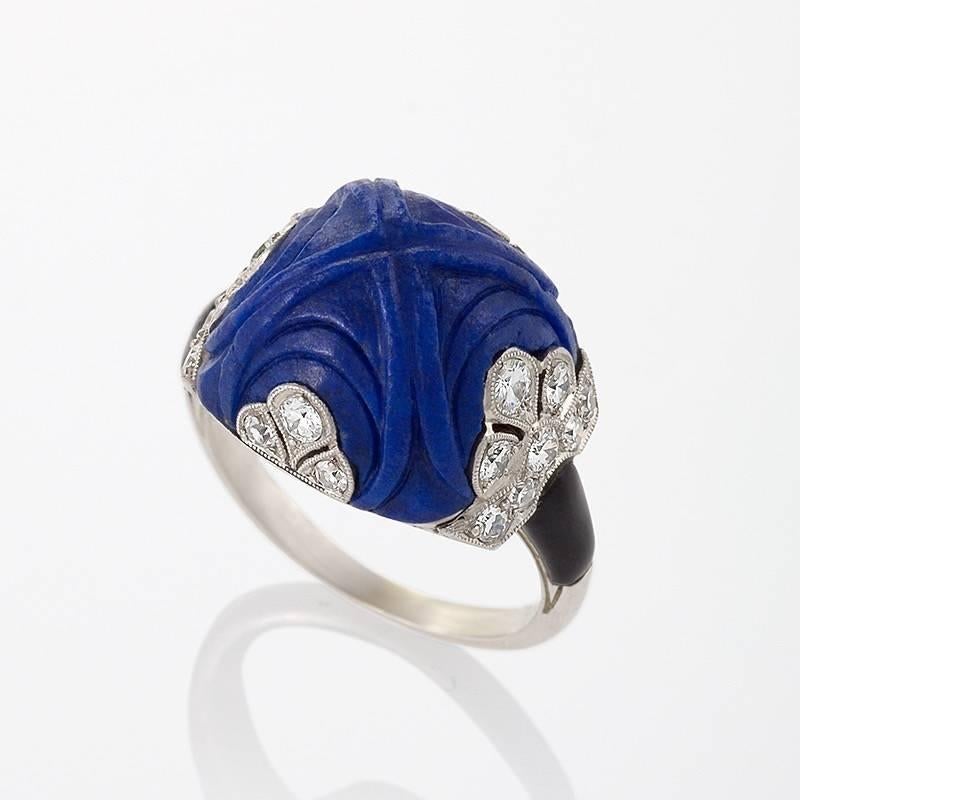 An Art Deco platinum and enamel ring with lapis lazuli and diamonds attributed to Marchak. The ring has a carved sugar loaf cut lapis lazuli stone and 22 round miligrain set diamonds with an approximate total weight of .60 carats. French