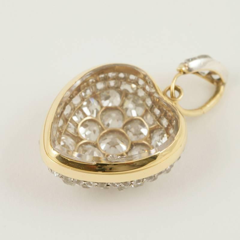 An Antique 18 kt gold and oxidized silver pendant with diamonds. The heart pendant has 89 old mine-cut diamonds with an approximate total weight of 10.00 carats. The reverse of the pendant is crystal backed to create a locket compartment  which