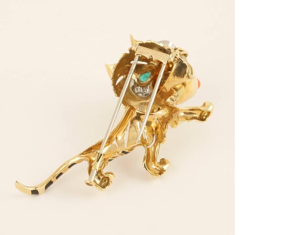 A French Mid-20th Century 18 karat gold and platinum brooch with emeralds, diamonds, black enamel and coral by Van Cleef & Arpels. The tiger brooch has 2 cabochon emerald eyes with an approximate total weight of .40 carats, 9 round diamonds with