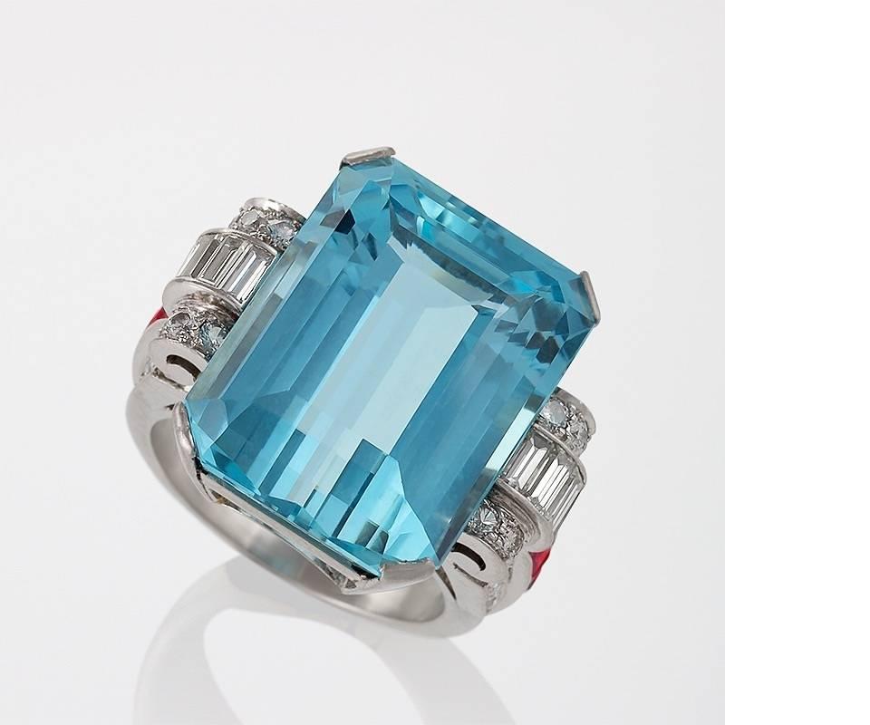 A Retro platinum ring with aquamarine, diamonds, and rubies. The ring has a rectangular-cut aquamarine with an approximate weight of 16.10 carats, 8 baguette diamonds with an approximate total weight of .80 carat, 28 round diamonds with an