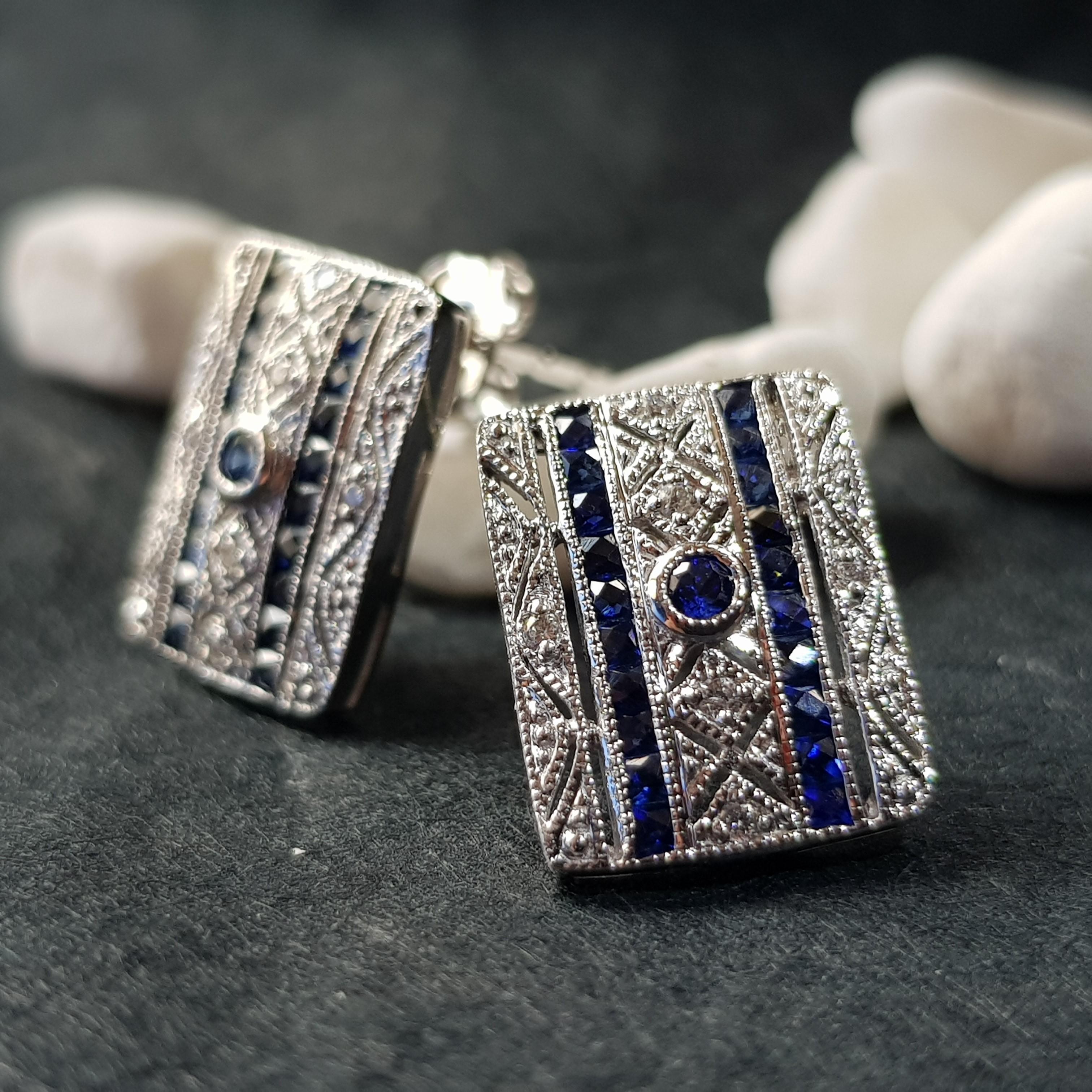 Ces boucles d'oreilles carrées en saphir et diamant de style Art déco présentent un saphir rond au centre, flanqué de lignes verticales de saphirs allant de haut en bas de chaque côté. L'audacieux arrangement de saphirs est encadré dans une