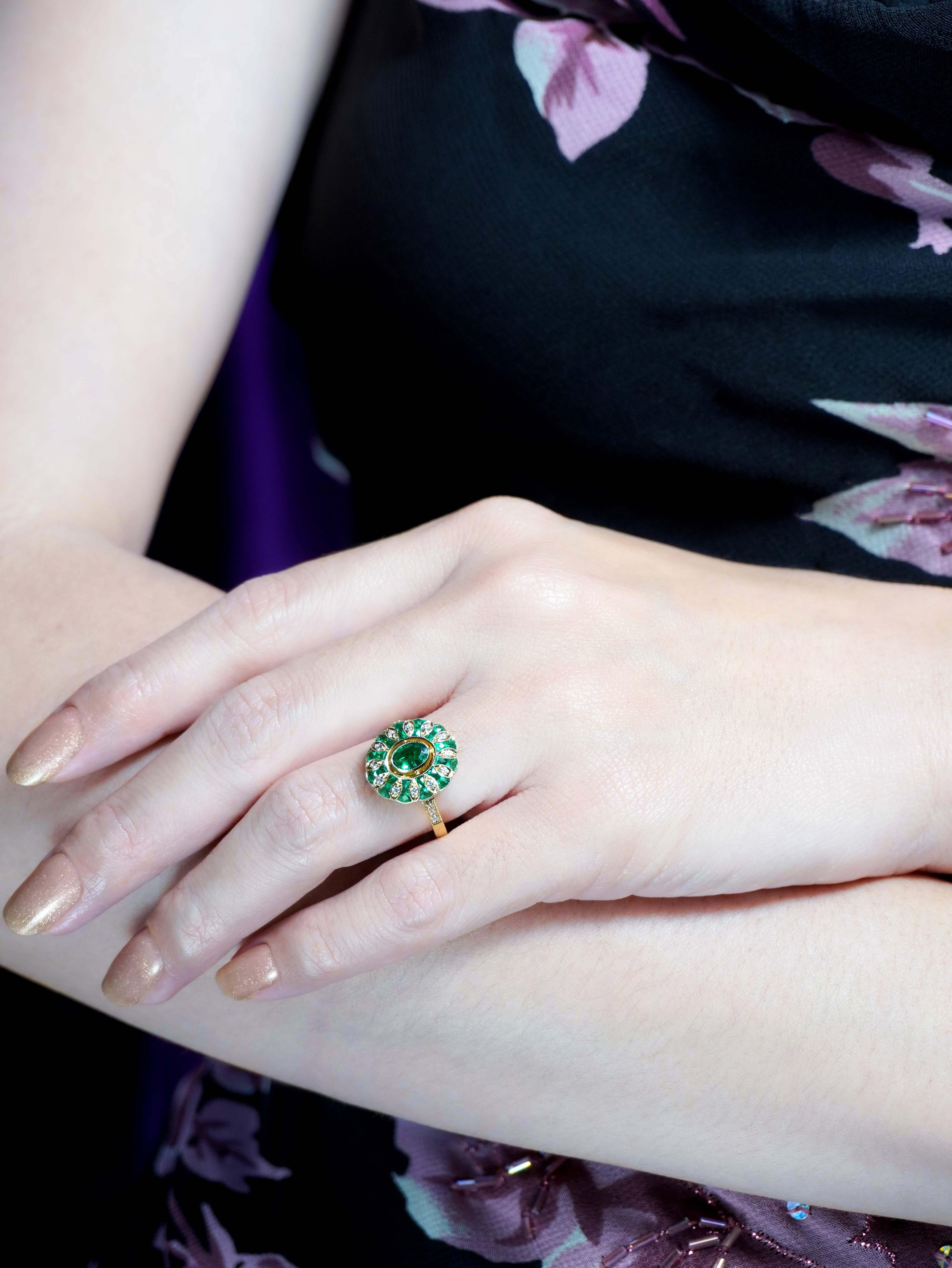 Embrassez l'élégance vintage avec cette bague de fiançailles ovale en émeraude et diamant de style Art Deco. Une émeraude ovale est au centre, entourée d'émeraudes et de diamants alternés dans un motif floral captivant. Les épaules de la bague sont
