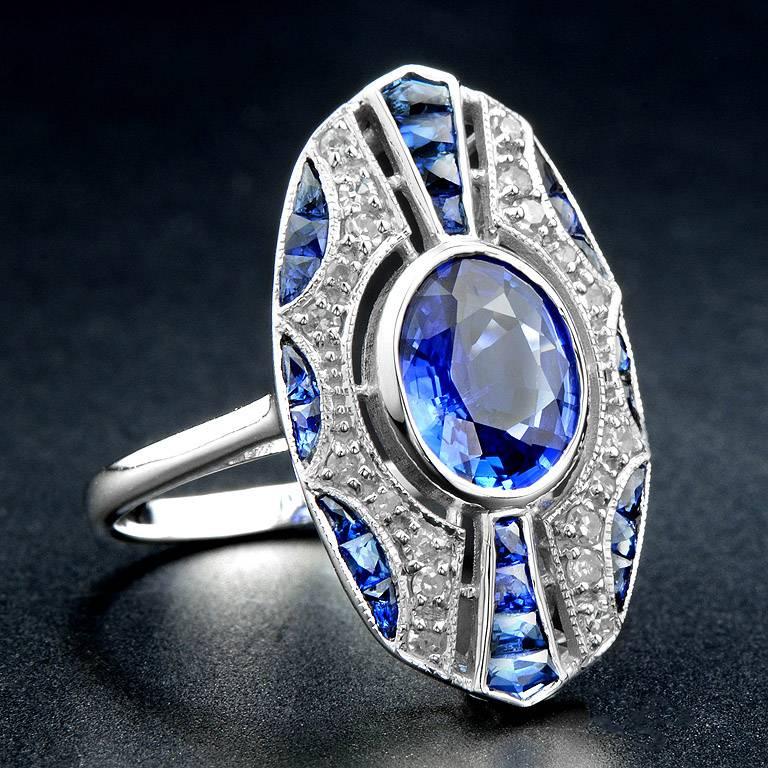 Art Deco Style Ring set with Ceylon Sapphire 2.00 Carat in the center and another 1.47 Carat Blue Sapphire outlined with small Diamond 0.23 Carat.  This ring was made in 18K White Gold in size US#7