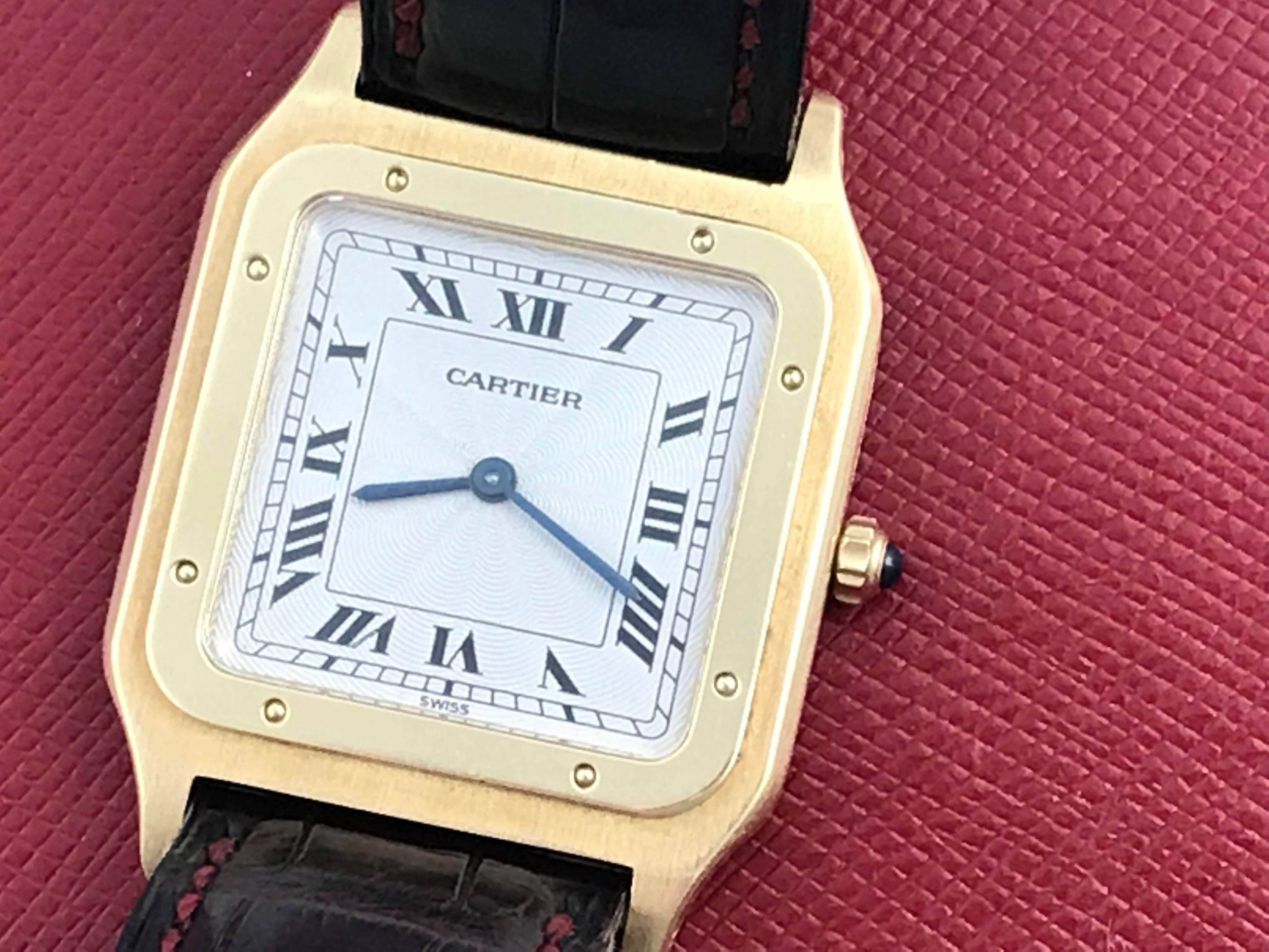 Manufacturer: Cartier
Model Name: Santos
Condition: Pre Owned
Watch Category: Contemporary
Gender: Midsize
Movement: Manual Winding
Dial: Silvered Dial with black Roman numerals
Case: 18k Yellow Gold square style case with Blue Sapphire cabachon