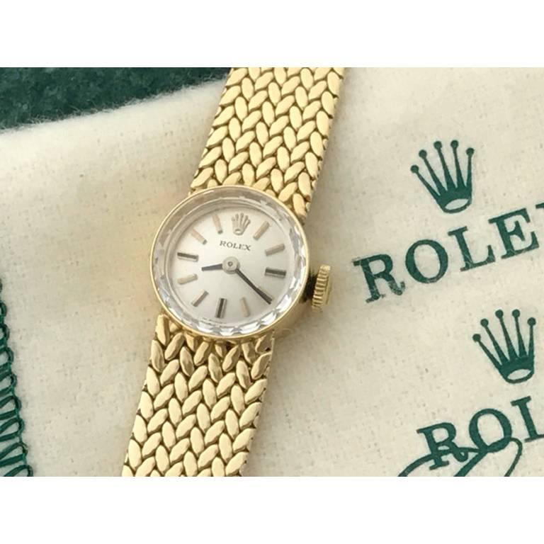 Rolex Vintage Ladies Model 9656. Manual Winding Movement, Rolex Caliber 1400 with Eighteen Jewels. 14k Yellow Gold Rolex round style case measuring 15mm diameter.  14k Yellow Gold integrated Rolex bracelet. Silvered Dial with black and gold hour