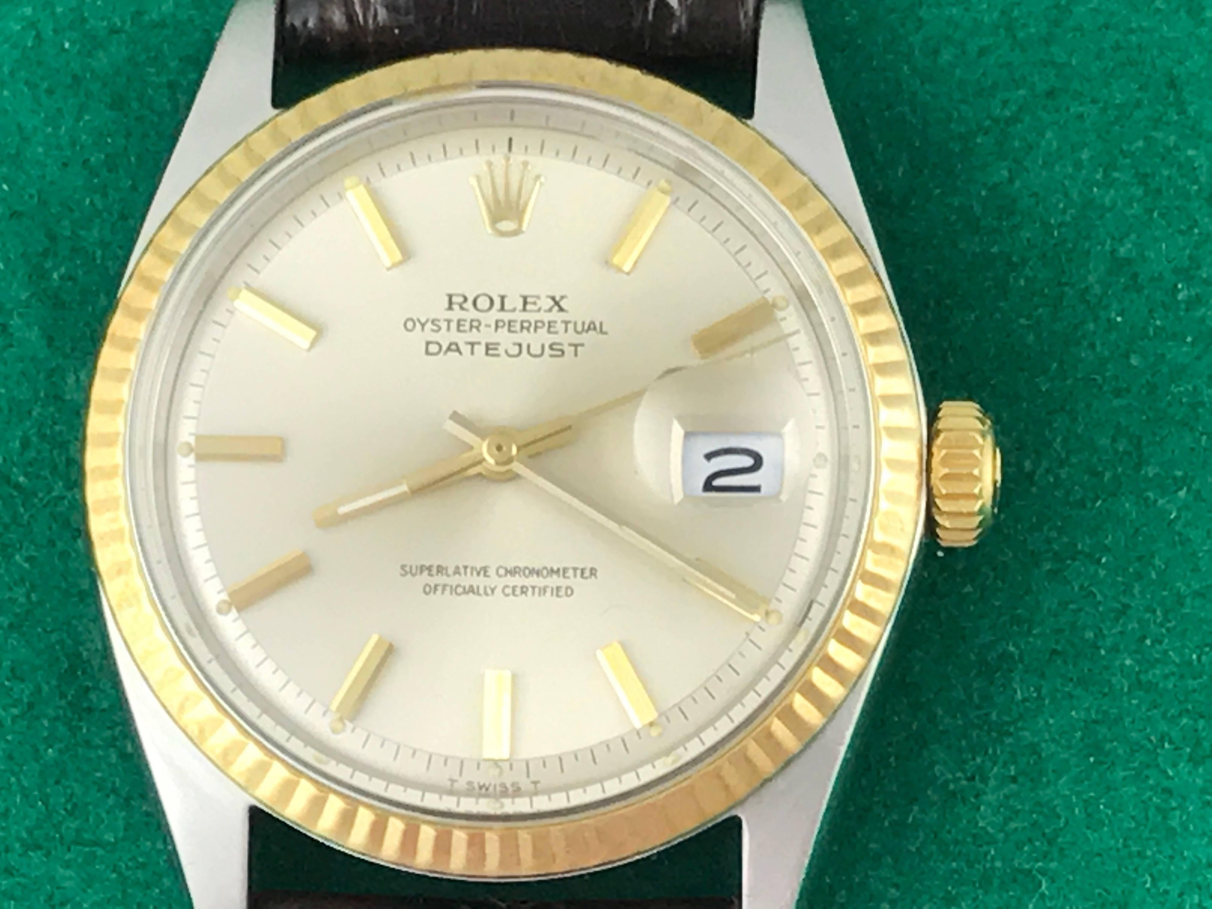 The Rolex Datejust Model 1601 pre-owned men's automatic wrist watch. Featuring an oyster silver dial with yellow gold hour markers and stainless steel case with 14k yellow gold fluted bezel. Measures 35mm. Comes with a dark brown alligator strap,