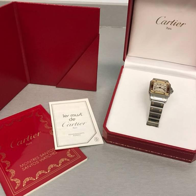 Cartier Ladies Santos Model W20012C402 Stainless Steel and 18K Yellow Gold Wrist Watch.  Quartz movement.  Stainless Steel square style case with 18k Yellow Gold bezel with blue sapphire cabachon setting crown (24x34mm). Water Resistant to 30 Meters