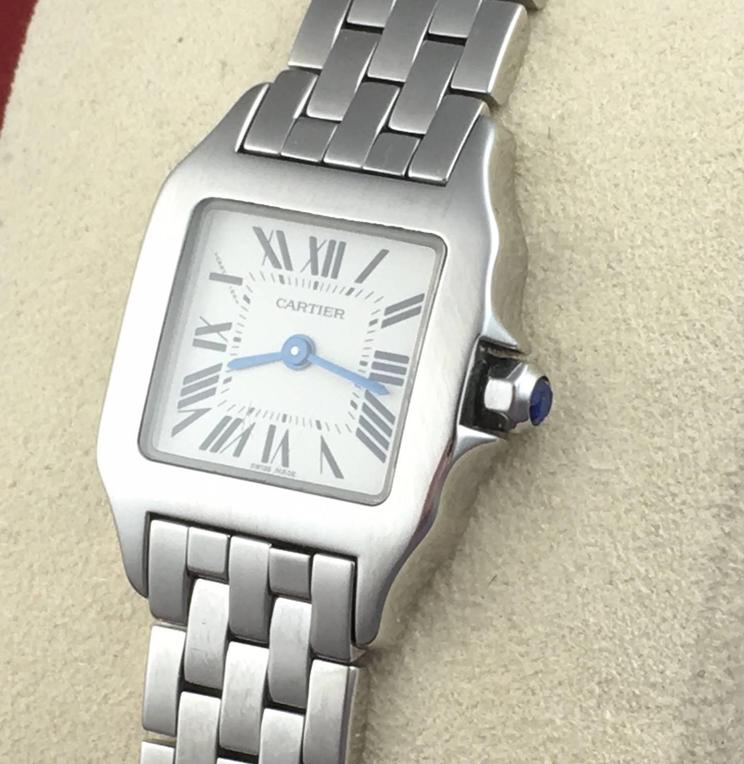Cartier Ladies Santos DeMoiselle Model W2510002 Stainless Steel Wrist Watch.  Quartz movement.  Stainless Steel square style case with blue sapphire cabachon setting crown (20x28mm). Water Resistant to 30 Meters - 100 Feet. Stainless Steel bracelet