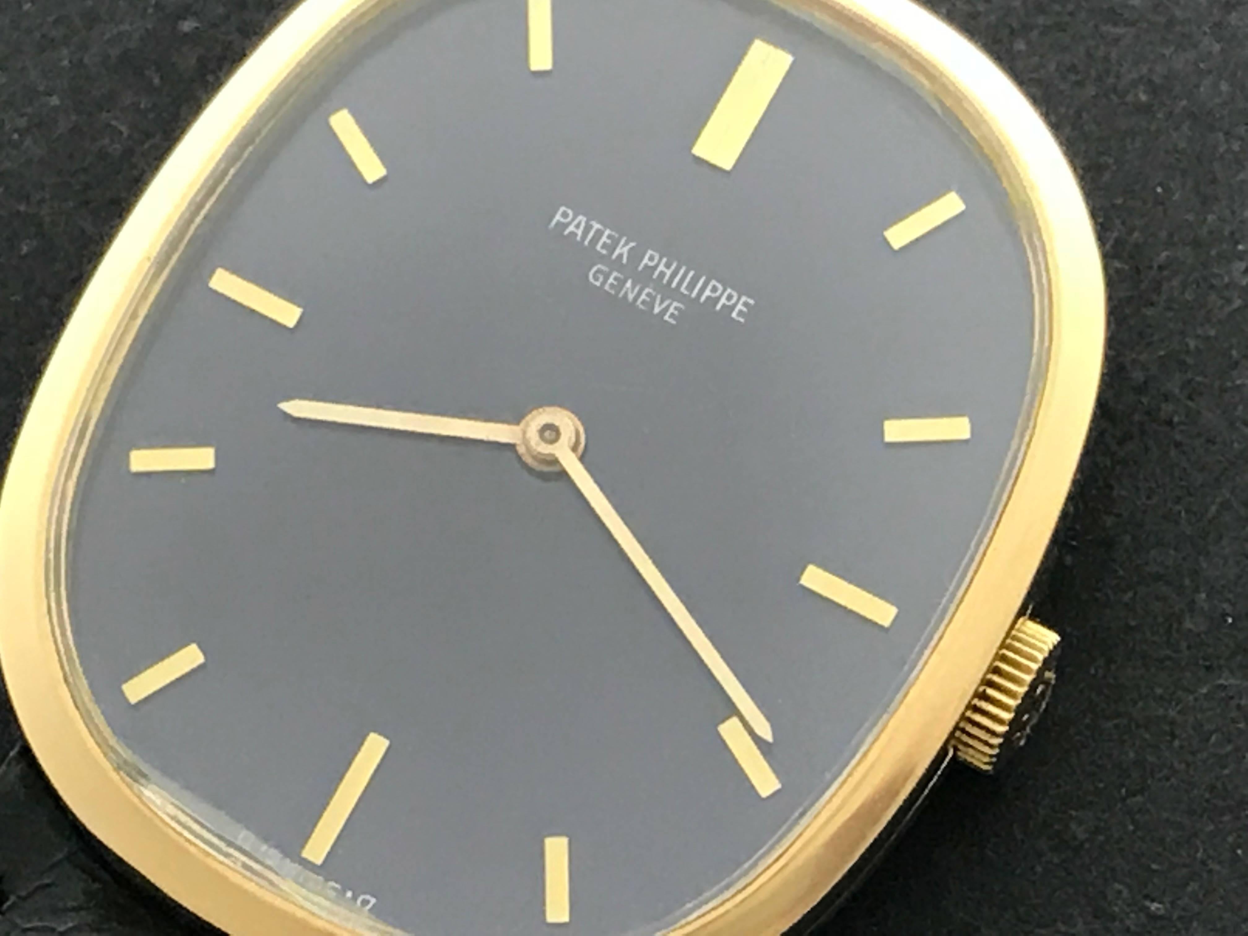 Patek Philippe Men's 3548 Wrist Watch in 18K Yellow Gold.  This timepiece features an 18K yellow Gold ellipse case, measuring 27x32mm in diameter.  Blue Dial with Yellow Gold hour markers. Black strap with 18k Yellow Gold Patek Philippe buckle is