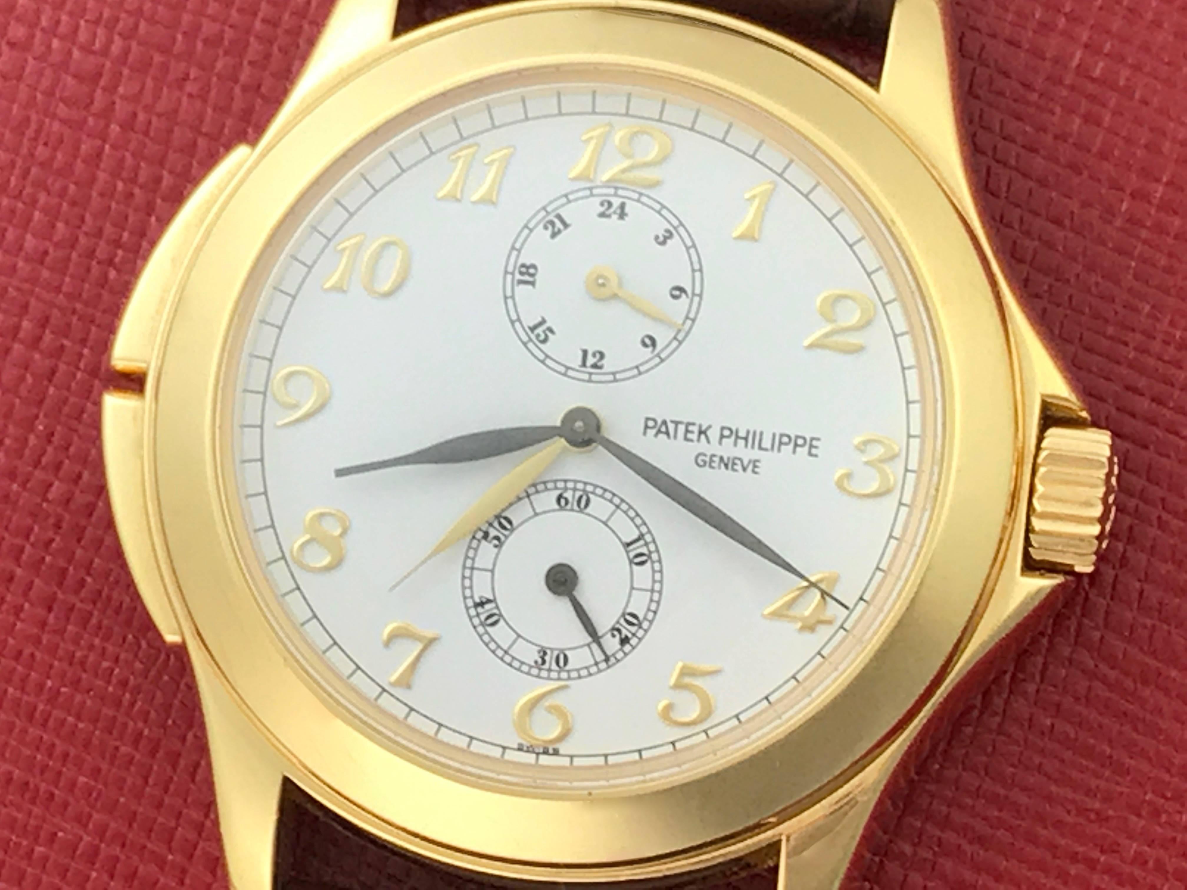 Patek Philippe 18k Yellow Gold Travel Time Men's manual wind Wrist Watch. 18k Yellow Gold round style case with exposition back to view movement (36mm). White Dial with black arabic numerals. Brown alligator strap with 18k yellow gold Patek Philippe