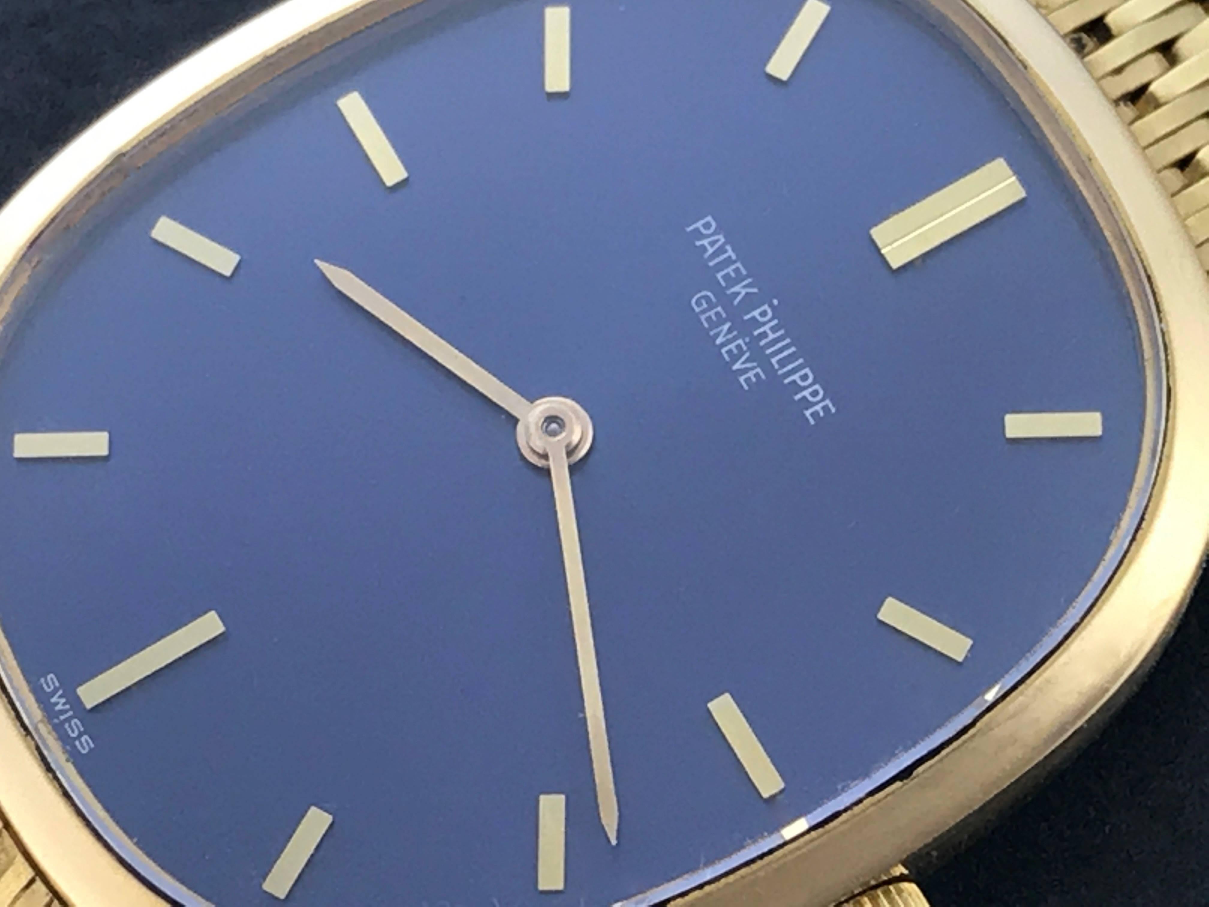 Patek Philippe Men's 3548/1 Manual Wind Wrist Watch in 18K Yellow Gold.  This timepiece features an 18K yellow Gold ellipse case, measuring 27x32mm in diameter.  Blue Dial with Yellow Gold hour markers. 18k Yellow Gold integrated Patek Philippe