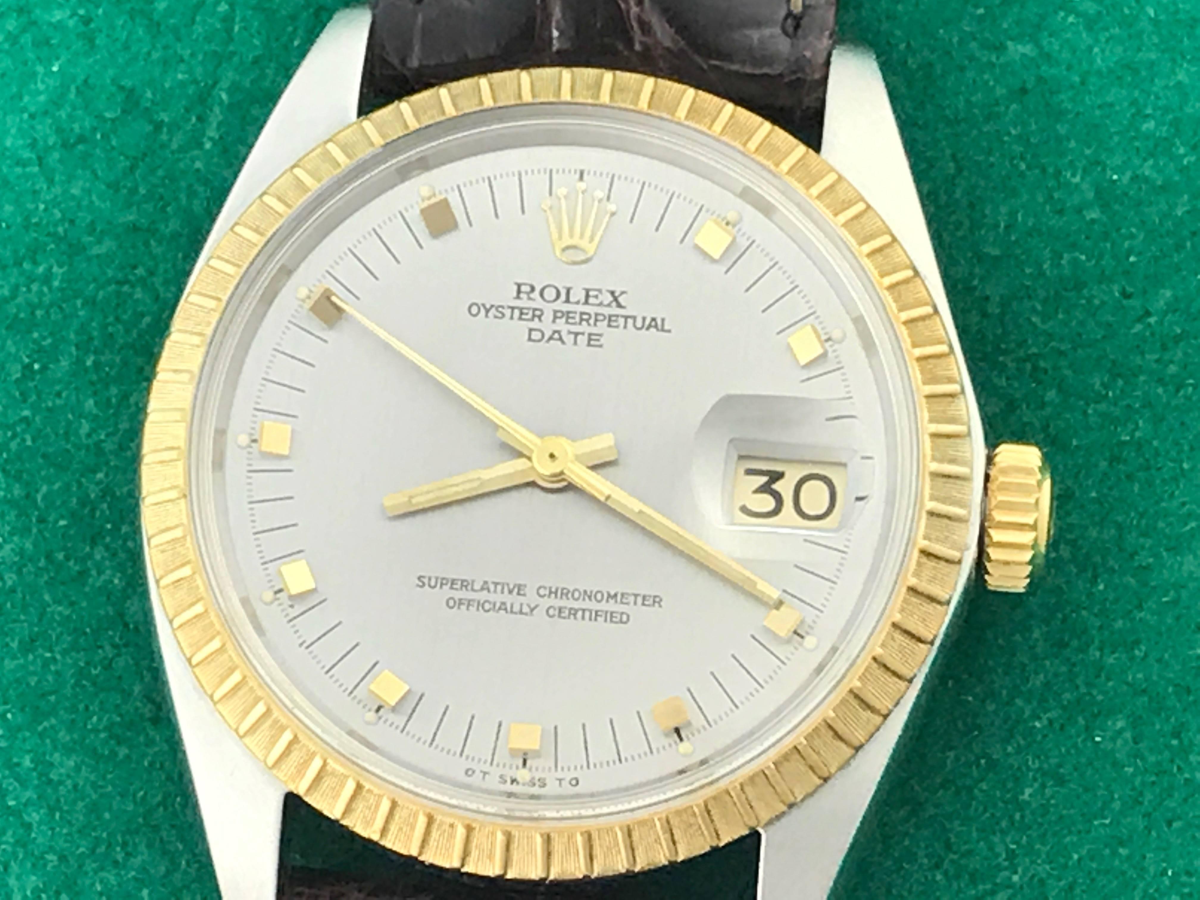 The Rolex Date Model 15053 Mens automatic wrist watch. Featuring a silvered dial with yellow gold hour markers and stainless steel case with 18k yellow gold engine-turned bezel. Measures 34mm. Comes with a dark brown alligator strap, box,