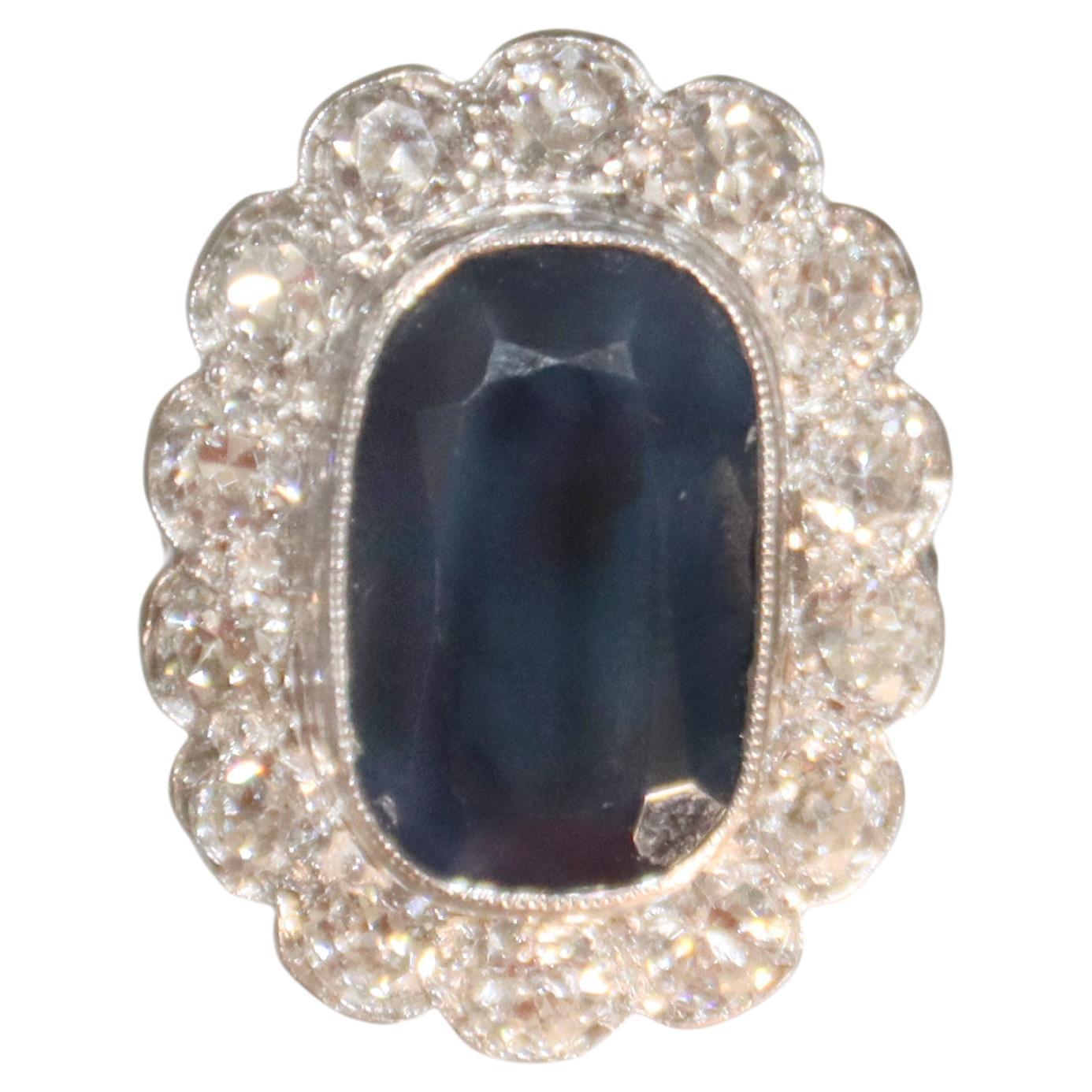 This is a sophisticated 18-karat white gold ring showcasing a timeless design. At its center lies a magnificent sapphire weighing 7.10 carats, exuding deep blue elegance. Surrounding the sapphire is a sparkling brilliant-cut diamonds, with a total