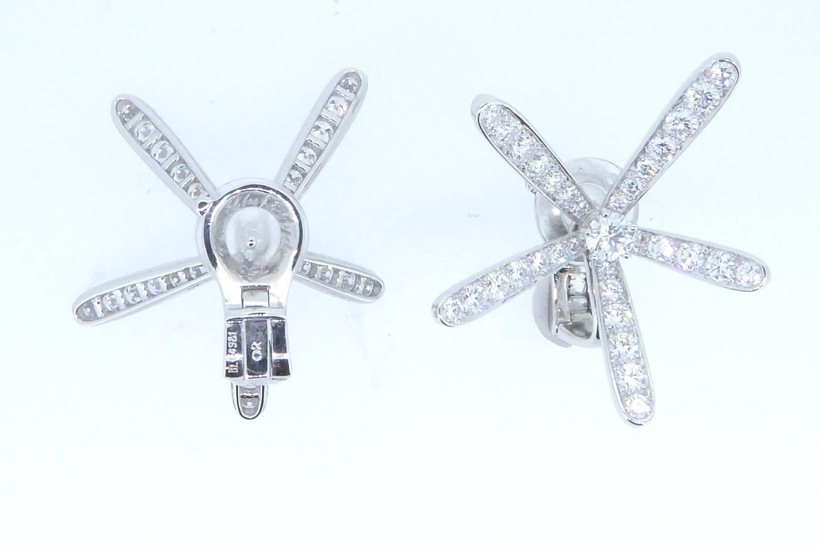 A pair of Van Cleef and Arpels Caresse D'Eole White Gold and Diamond Ear Clips. Each ear clip centring upon one larger diamond with five graduating diamond-set pistols. Estimated total diamond weight 3.60 carats. Set in 18ct white gold. Each clip