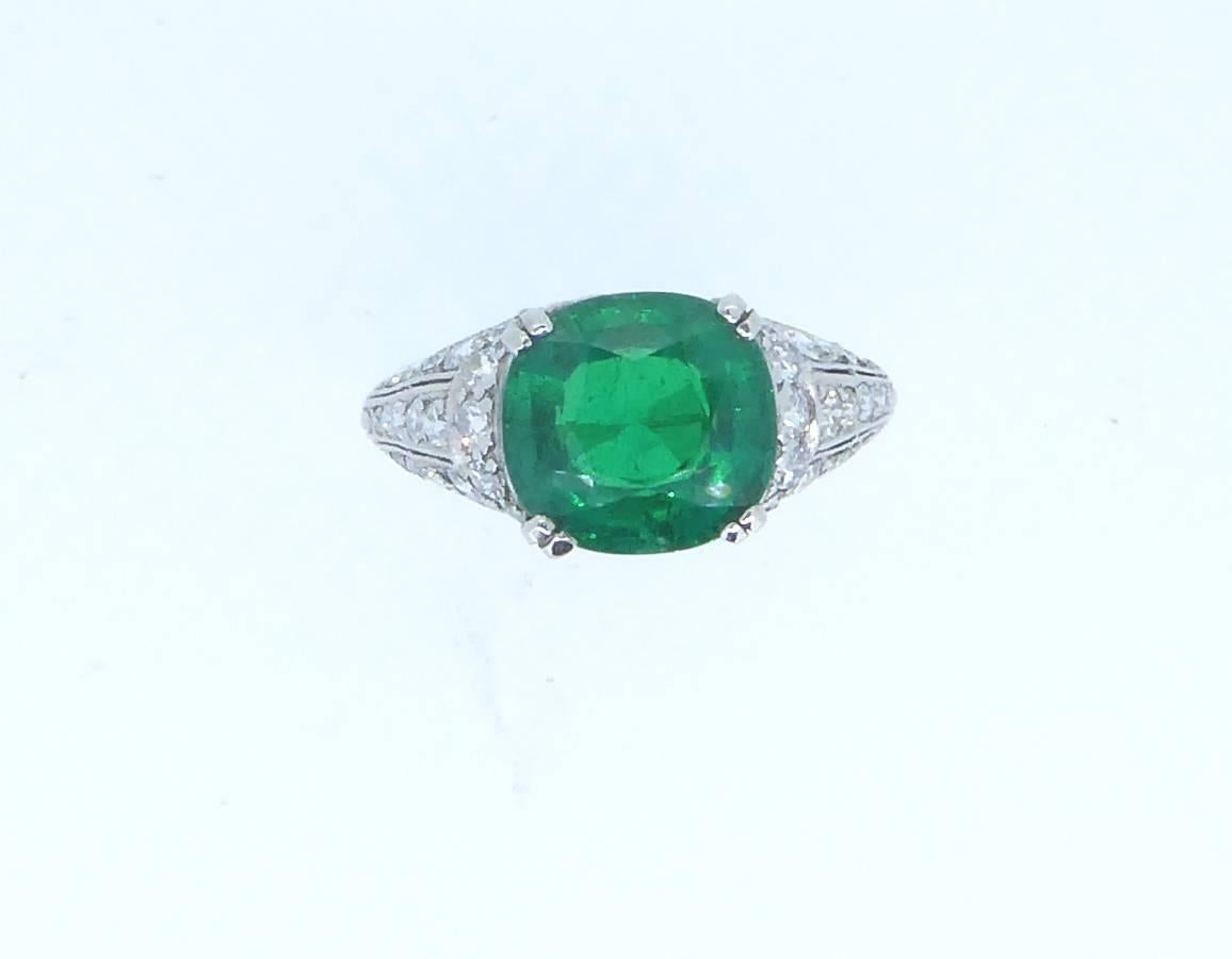 An Art Deco Tiffany 3.18cts Colombian emerald and diamond ring set in platinum. The claw-set cushion-shaped emerald of rich, vibrant colour with a certificate from Anchorcert stating it to be Colombian and with insignificant clarity enhancement.