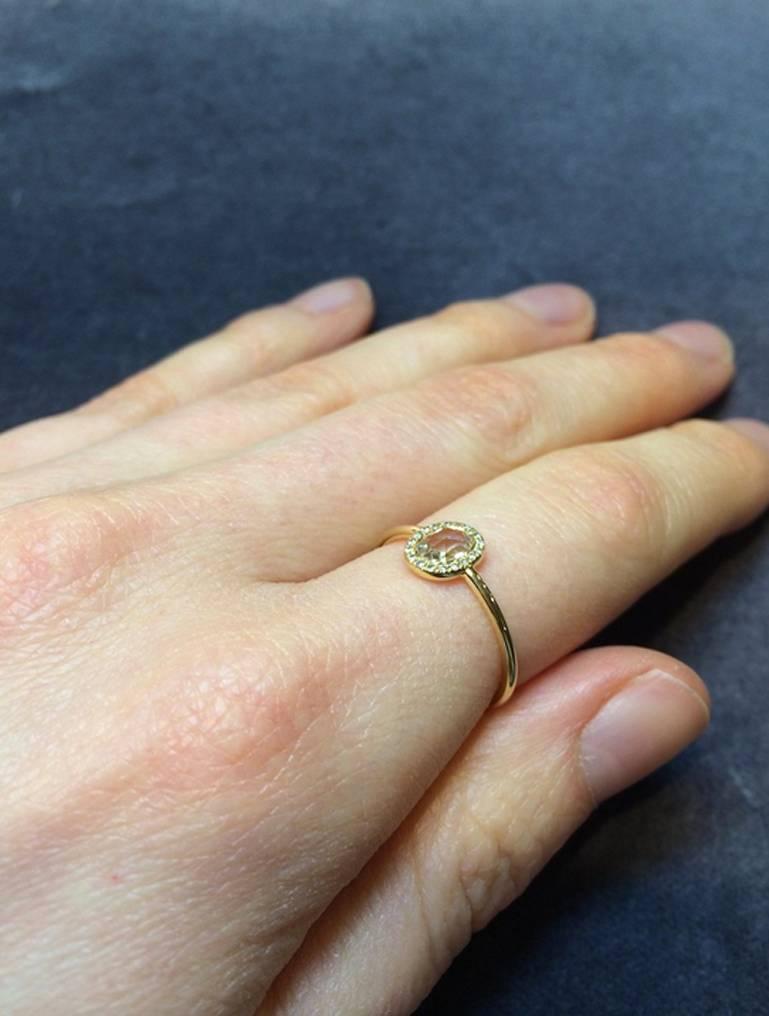 This beautiful one-off piece is a twist on the popular classic round rose cut halo ring. The centre stone is a white oval shaped rose cut diamond with a pave set halo surround of brilliant white diamonds. Set in 18ct yellow gold the centre stone is
