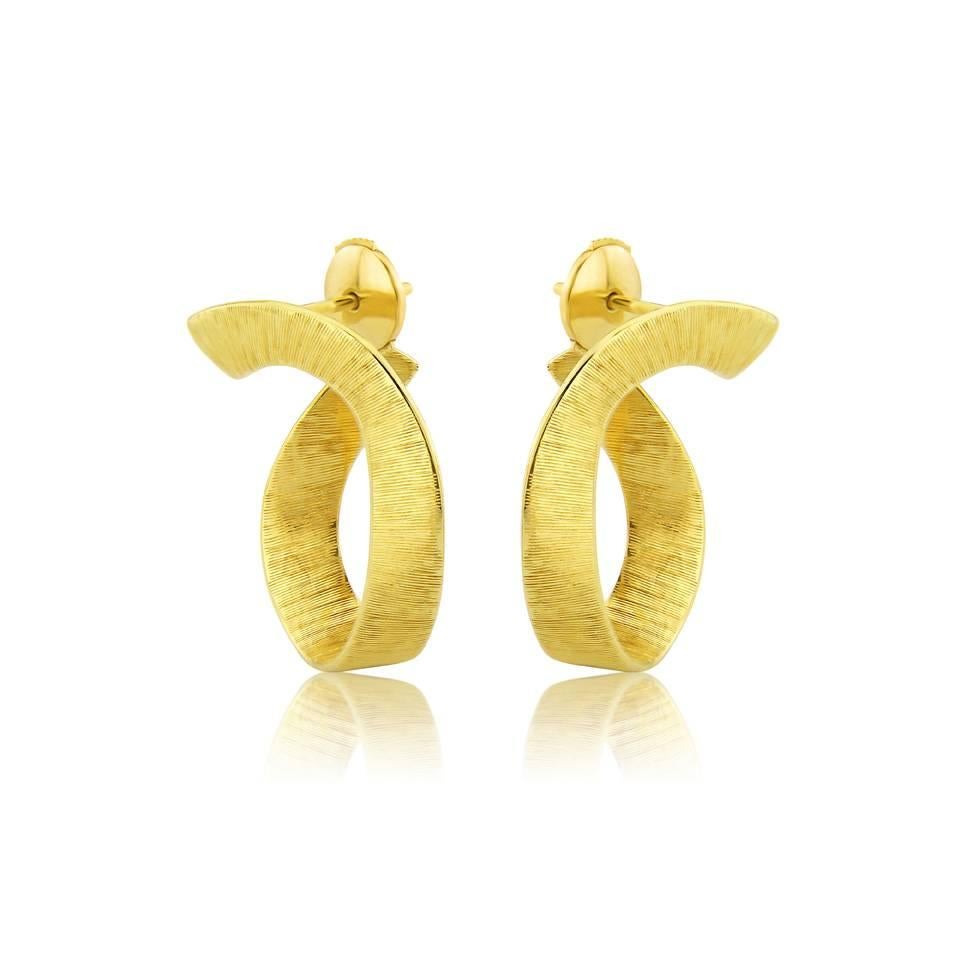 This elegant hoop curves around the ear lobe creating an unusual organic silhouette. 
The silken effect is hand engraved giving these earrings their unique finish.
 
These hoops are available in;
Solid silk engraved 18 karat yellow gold, Solid silk