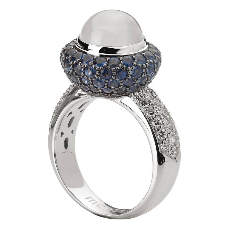 Crafted in white gold and set with blue sapphires in blue rhodium coating, white diamonds and a Moonstone round cabochon. This cocktail ring has a distinct Art Deco-era feel and it is part of Monseo 'Apolo Collection' which is a collection of Modern