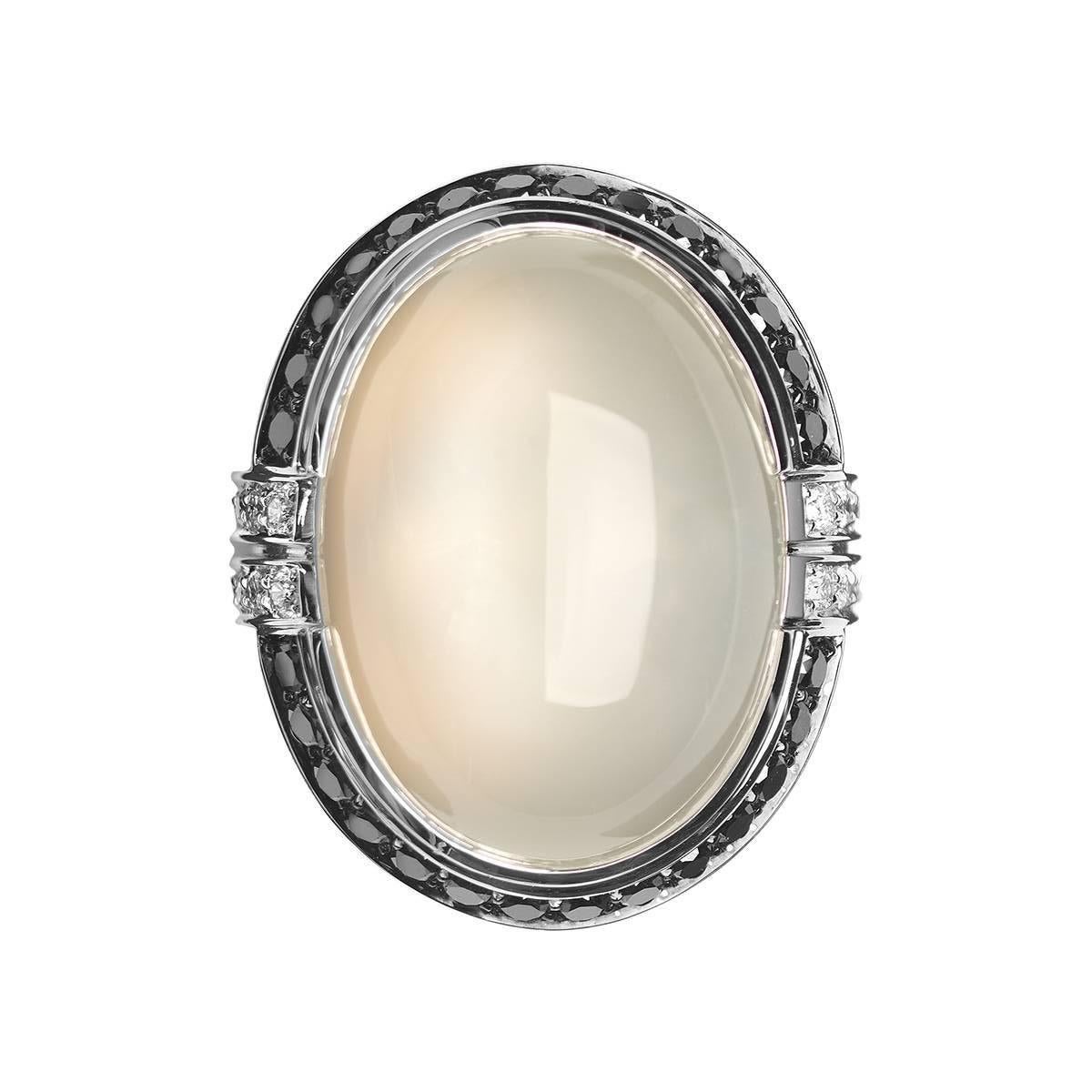 Crafted in white gold and set with black diamonds, white diamonds and an large oval cabochon white moonstone, this cocktail ring has a distinct Art Deco-era feel. This ring is part of Monseo 'Apolo Collection'  which is a collection of Modern