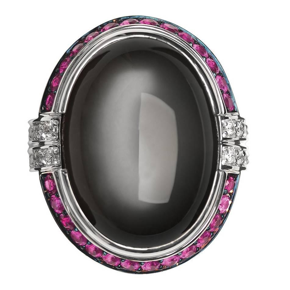Crafted in 19.2K white gold, white diamonds, an large oval cabochon grey moonstone and rubies set in black rhodium finished gold. 
This cocktail ring has a distinct Art Deco-era feel and it is part of Monseo 'Apolo Collection' which is a collection