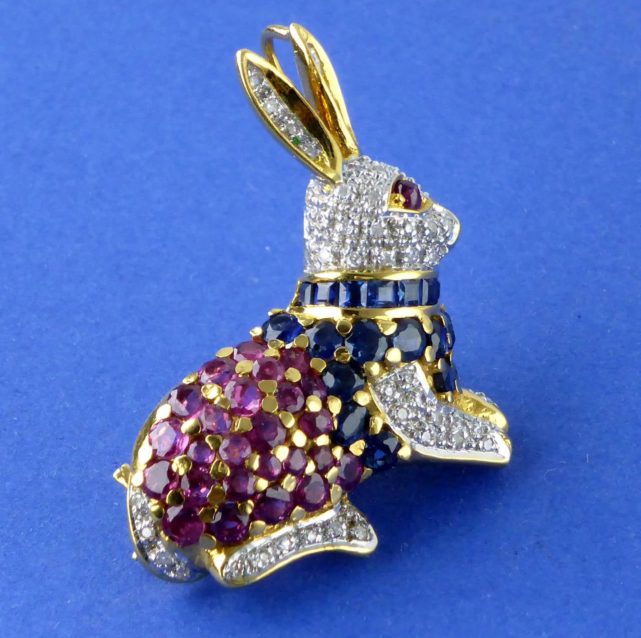 18ct gold brooch/pendant in the form of a rabbit set with diamonds, rubies and sapphires c1960 

Dimensions 3 cm x 3 cm approx