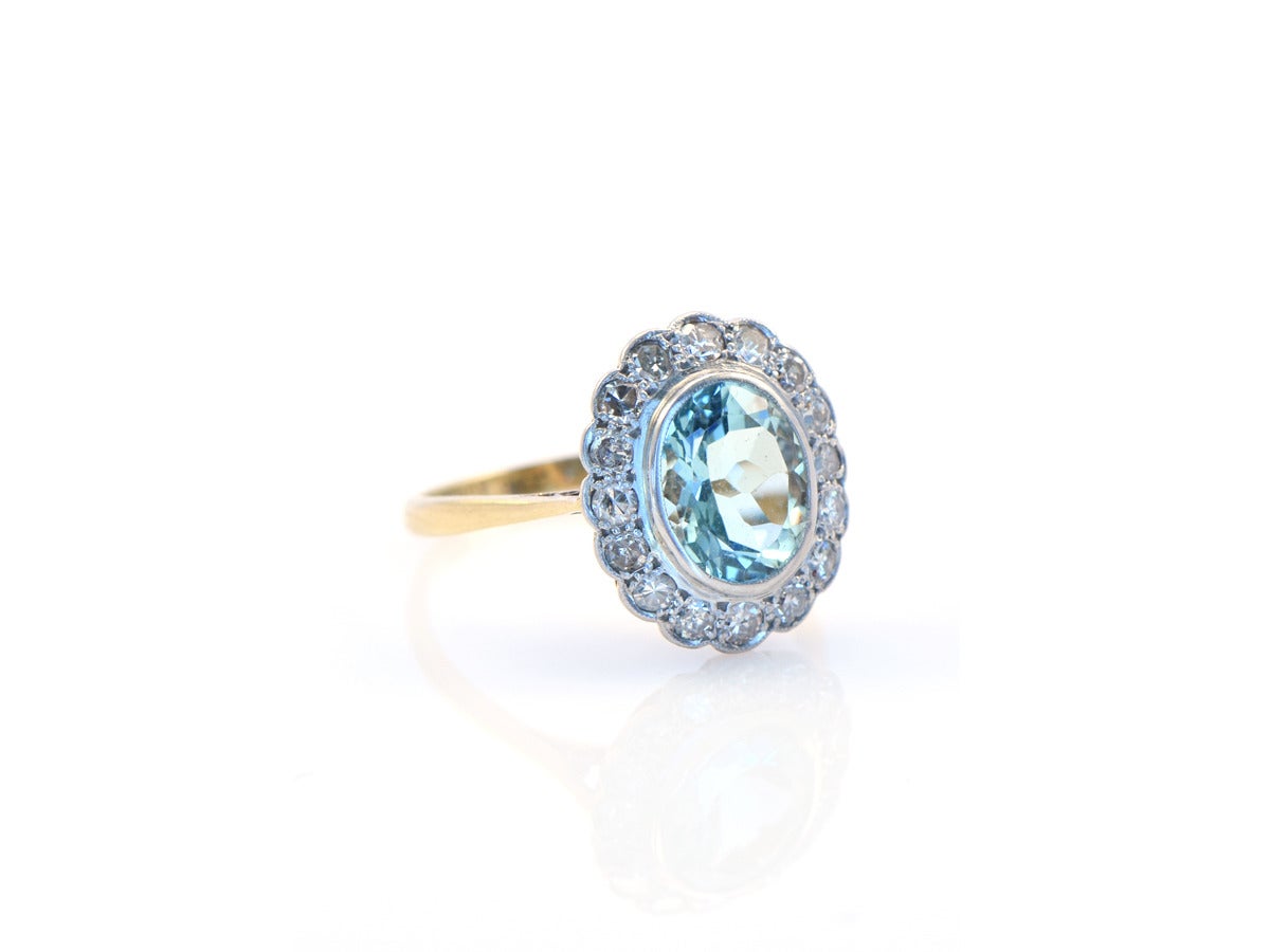 A bezel set oval aquamarine ring with single cut diamonds in platinum and18k yellow gold.  Ring size 8.