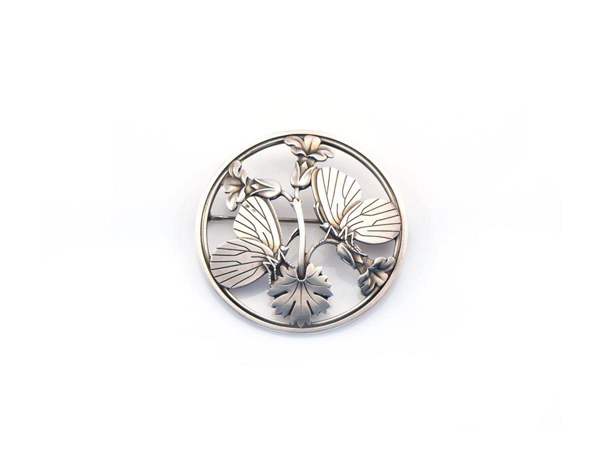 A sterling silver circular pin in true Jensen style, done with a natural motif.