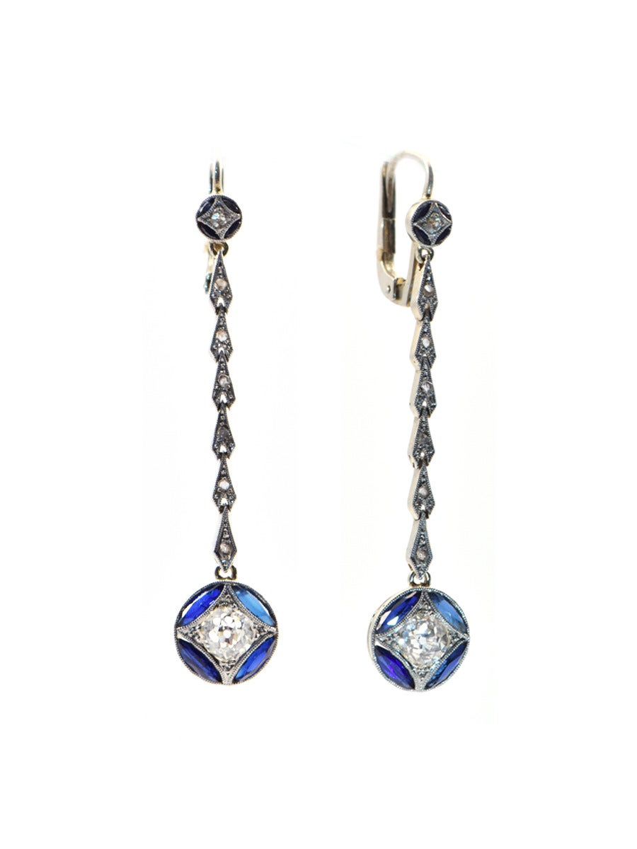 A long delicate platinum earring with antique European cut diamonds (approx 1 ct total) , accented with tiny rosecuts and finally finished off with a border of blue sapphire marquise cut stones.