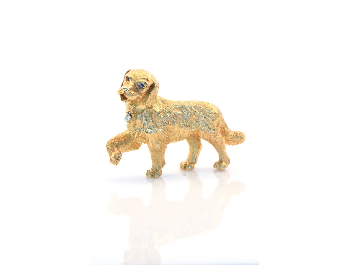 A golden retriever brooch in 18ky gold, created by Tiffany and Co. Germany. The collar has a hinged bezel set diamond and blue sapphires set into the eyes.
