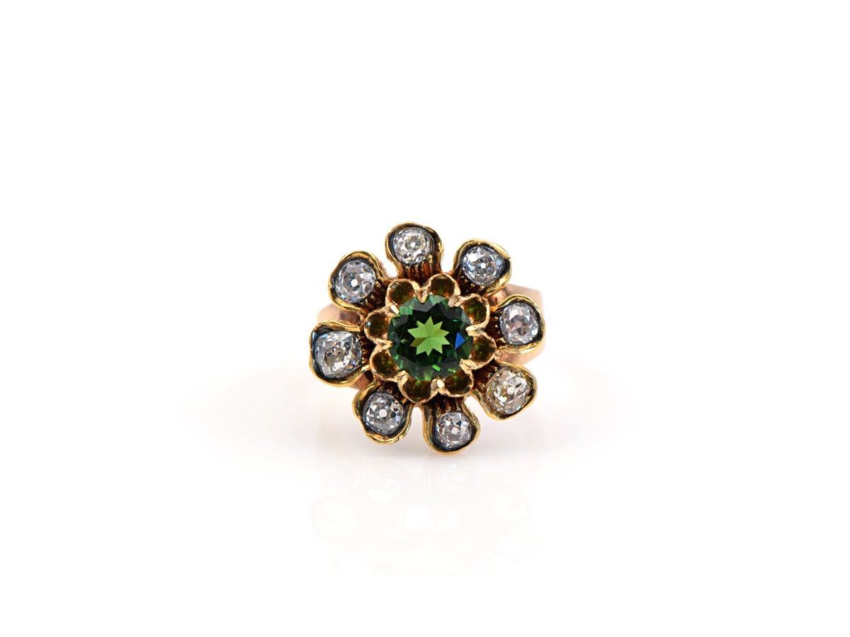 This mixed metal ring sets an array of old mine cut diamonds, with a round tourmaline center stone.  

*The flower measures approximately .75 inch
*The band is in 14k rose and the top is in 14k yellow gold.
*Diamonds weigh approximately .75-90ct