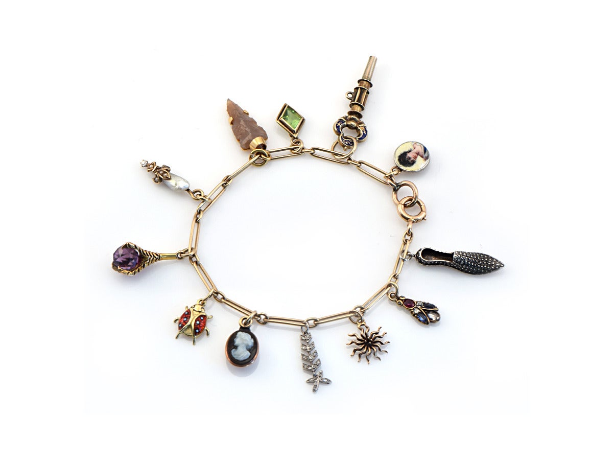 A multi charm bracelet with 12 different charms from the 19th and 20th Century, varying in size and material with precious and semi-precious stones.  

Materials Include:
*14k gold
*sterling silver
*enamel
*miniature hand painted
