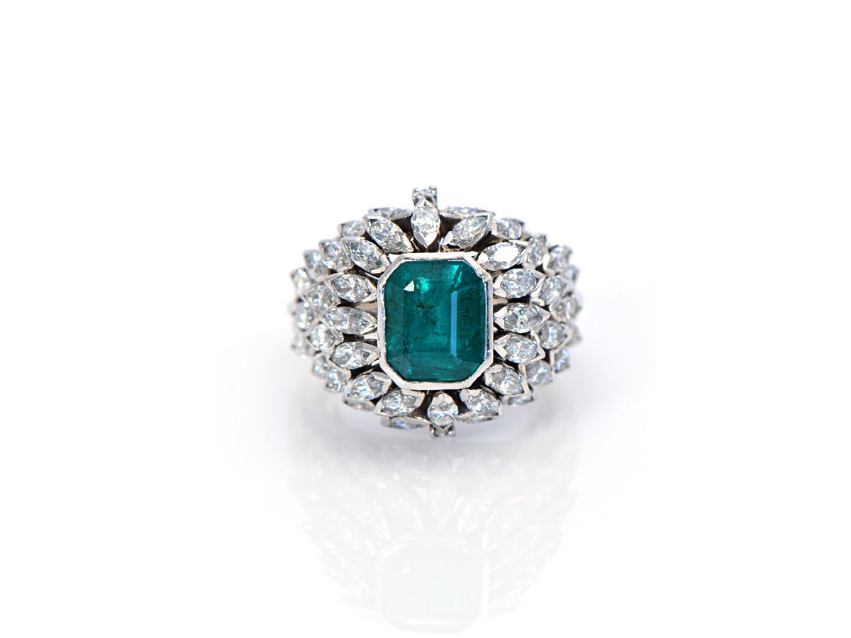 An exceptional cocktail ring... The center Colombian emerald cut emerald weighs approximately 2ct and is as vivid green as one would hope to have. 

*platinum
*the 2ct emerald is bezel set
*the marquise diamonds weigh approximately 2 cts
