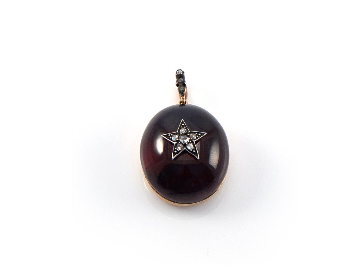 We are featuring an English-made high dome garnet carbuncle pendant in 14k gold, with rose cut diamond accents. The diamond star is adhered into the center of the pendant.