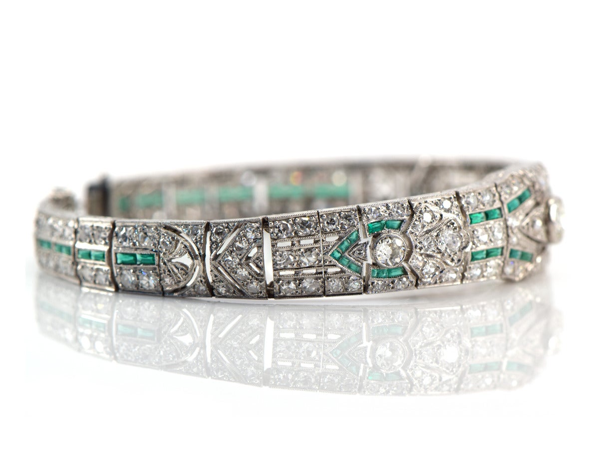 This platinum bracelet is beautifully hand crafted in the old world way. Old Euro and single cut diamonds are set throughout the bracelet and the French cut emeralds create a lovely pop of bright color while adding a dash of Deco style.  Hand