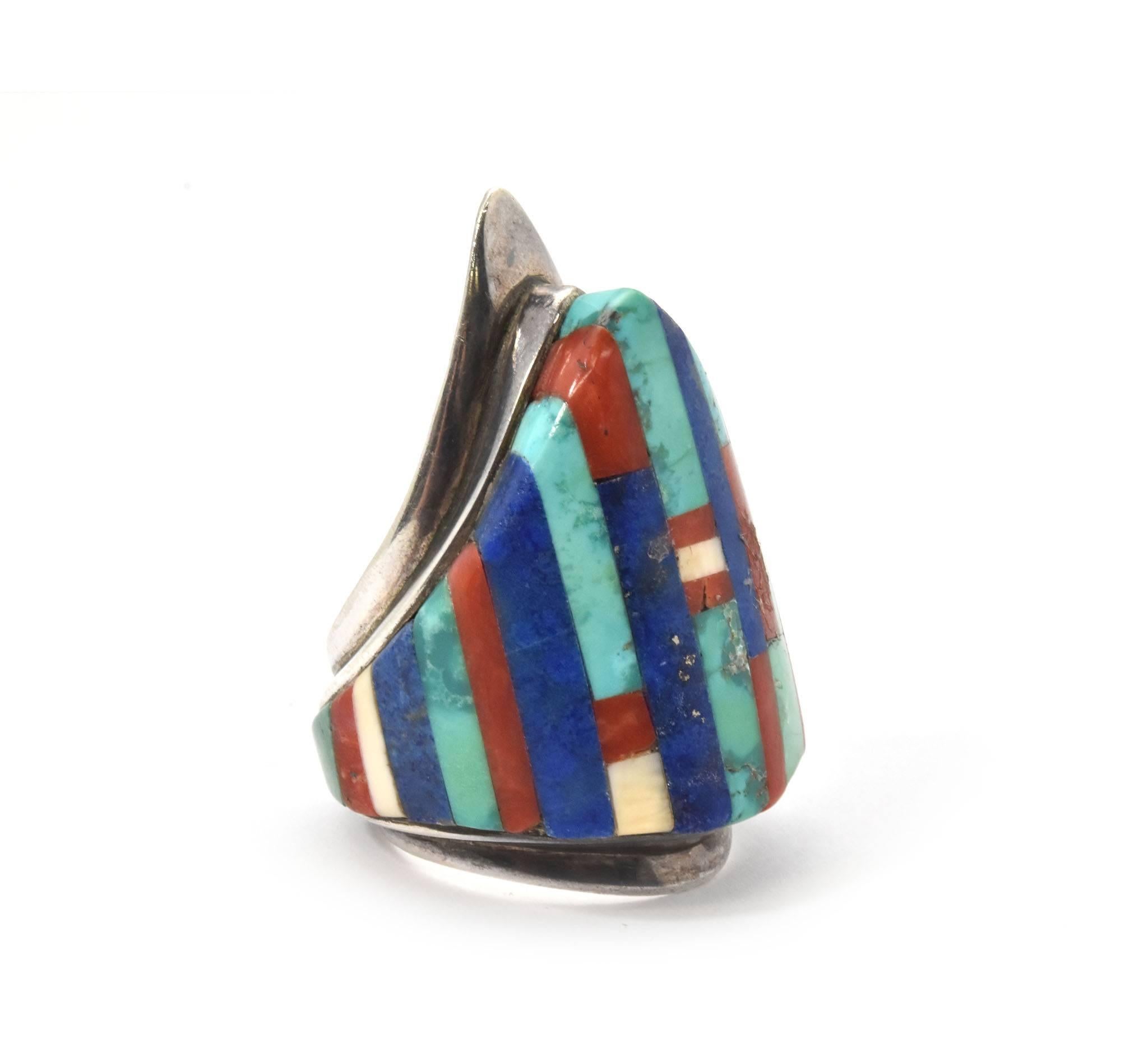 Designer: “Charles Loloma”
Material: sterling silver
Inlays: turquoise, lapis lazuli and coral
Dimensions: 1.75 inches tall and 1 inch wide
Ring size: 9
Hallmarks: “Charles Loloma”
Weight: 26.53 grams
