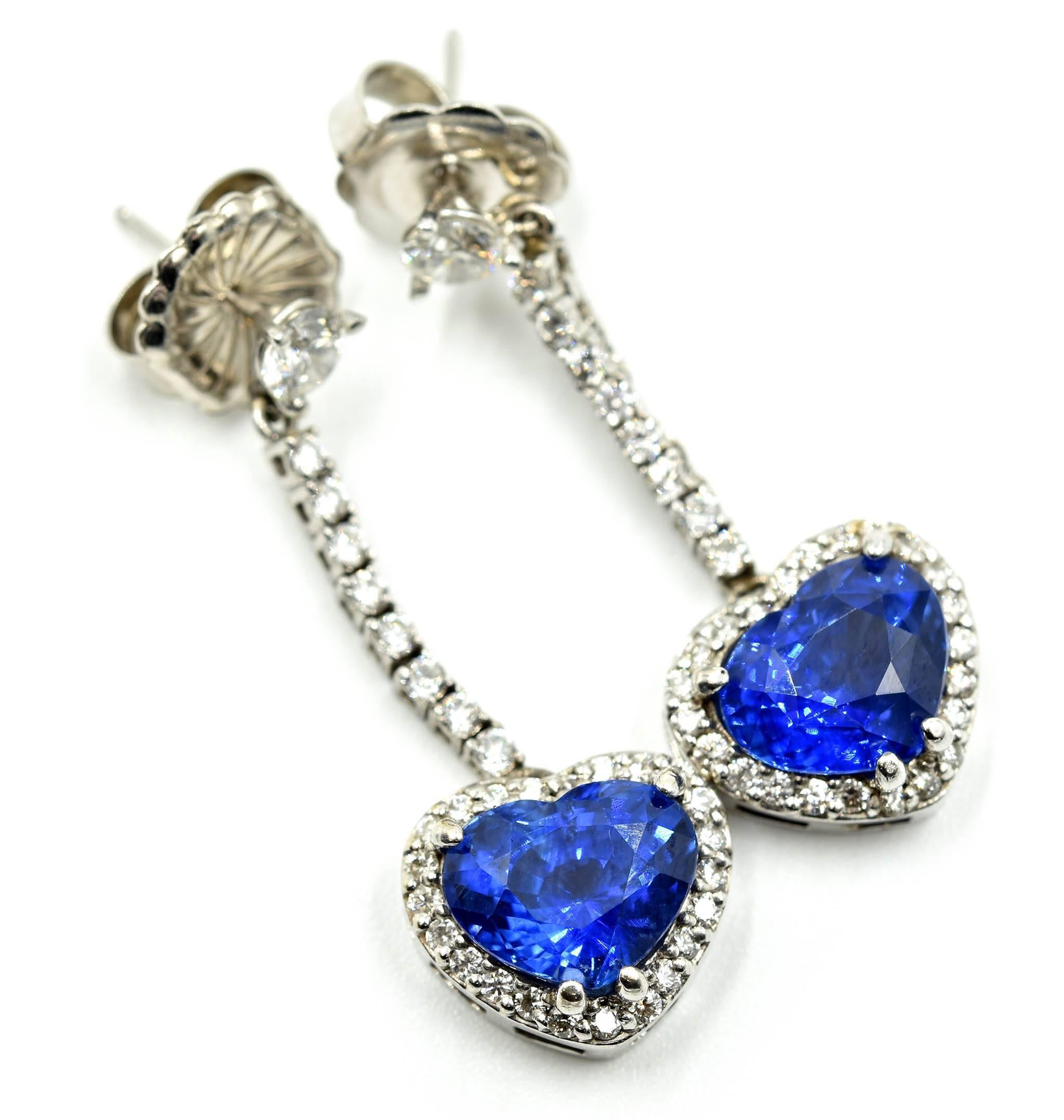 These stunning earrings feature GIA-certified heart-cut sapphires. The sapphires have a combined weight of 7.13 carats. The diamonds have an additional weight of 1.30 carats, and the stones are graded G in color and VS in clarity. Each earring