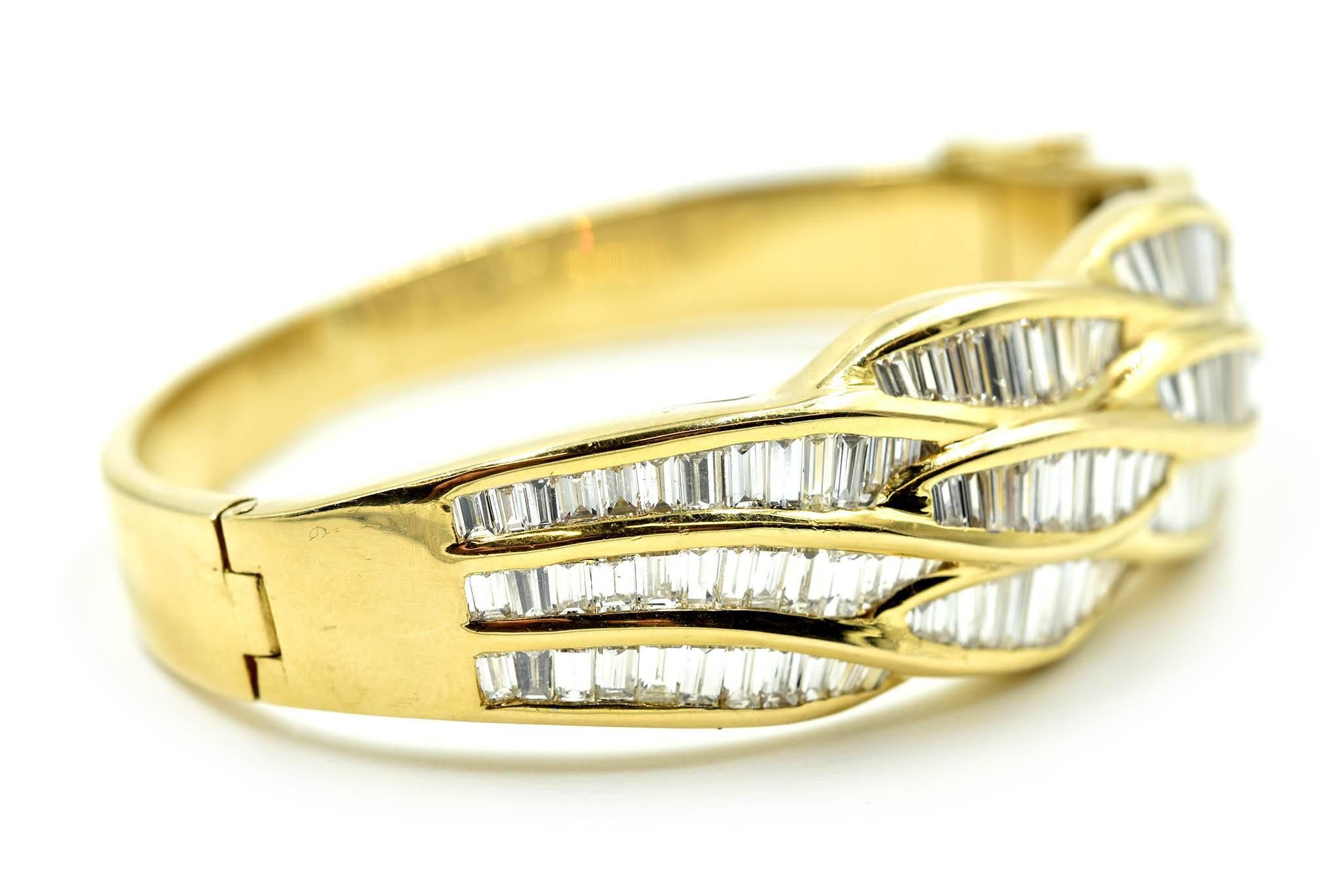 This gorgeous bangle is made in solid 18k yellow gold. The bangle features three rows of channel-set baguette diamonds for a total weight of 6.50 carats. The diamonds are graded G in color and VS2 in clarity. The bracelet measures 2.46mm wide, and