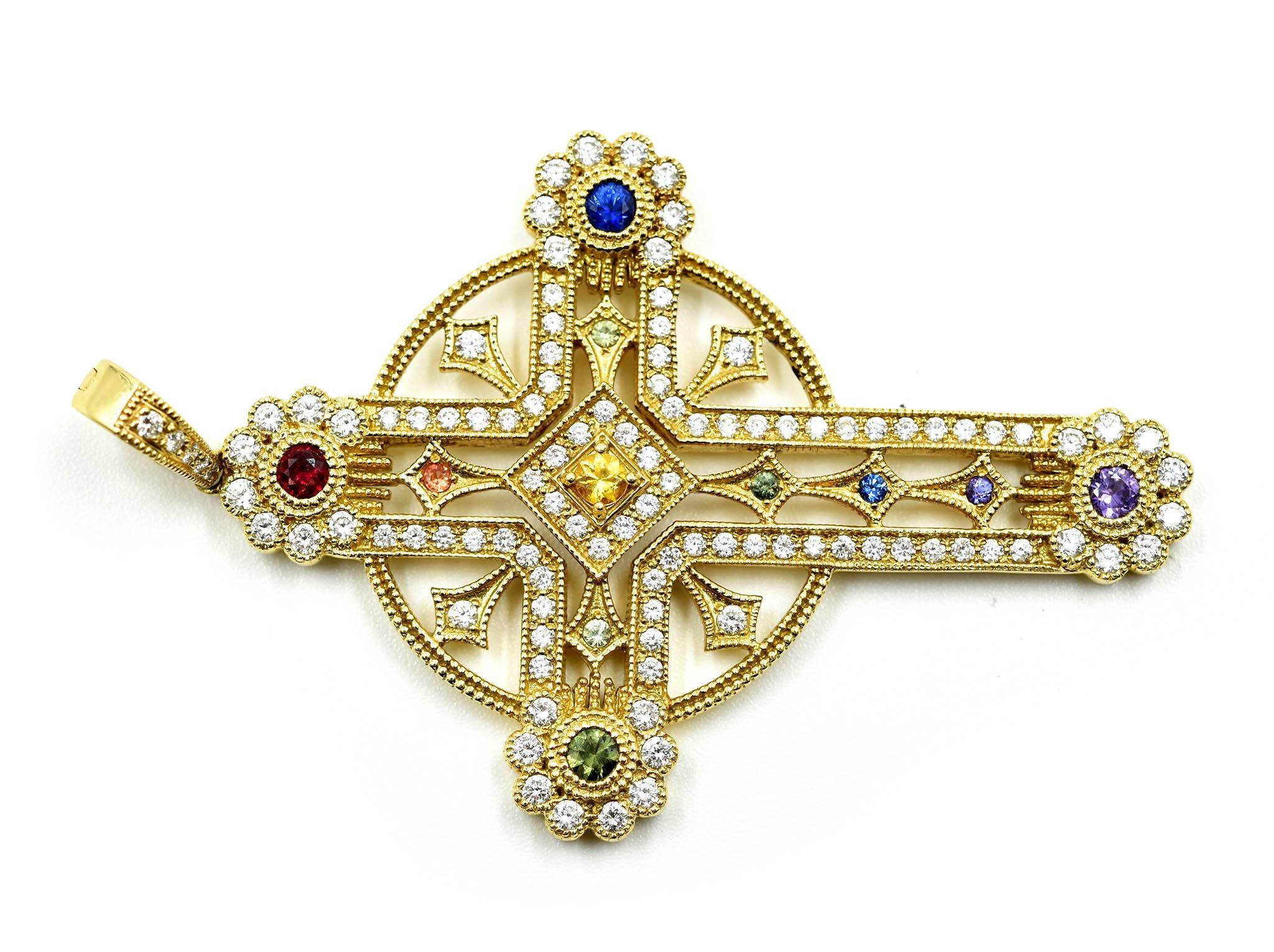 This fabulous cross pendant is made in 18k yellow gold. The cross is set with round diamonds and accented by various colors of sapphire. The diamonds have a total weight of 1.23cts, and the sapphires weigh 0.55ct. The cross measures 59x36mm, and it