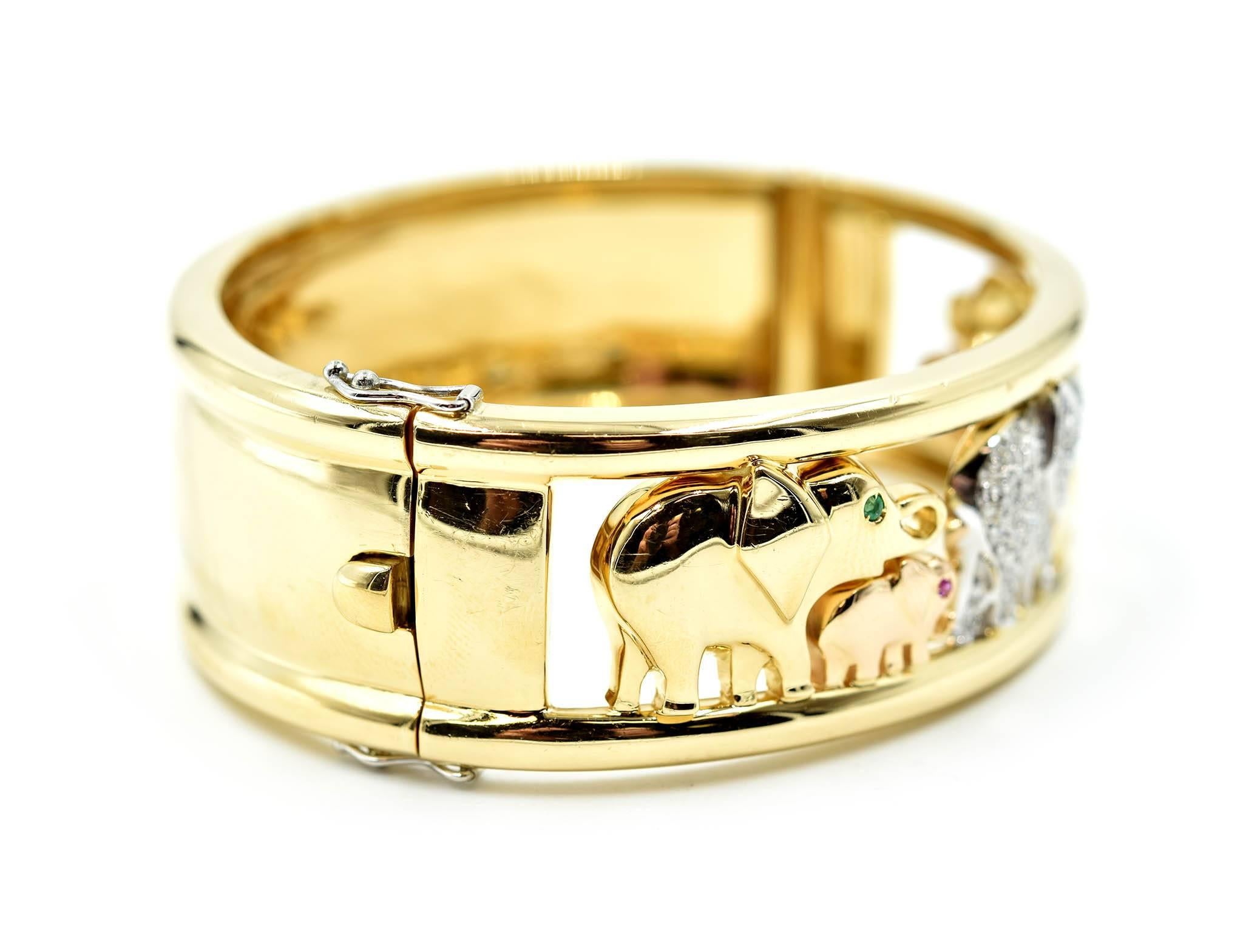 This marvelous bangle bracelet is designed with elephants set with gemstones! The gemstones are diamonds, rubies and emeralds. The bangle is fashioned in 18k yellow gold. The diamonds weigh 0.71 carats. Each diamond is graded G in color and VS in