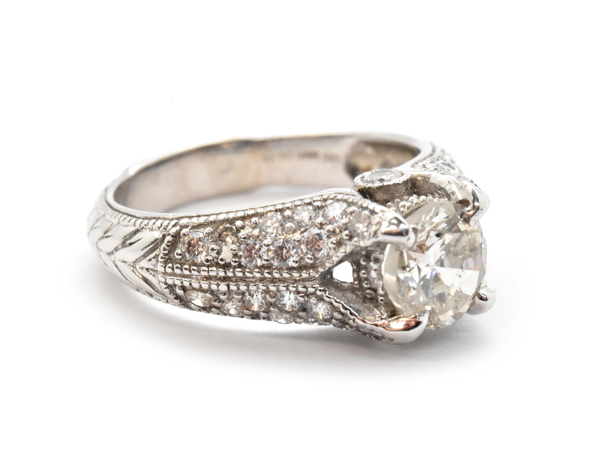 This stunning engagement ring holds a 1.38ct round brilliant diamond in an 18k white gold and diamond mounting. The center stone is graded K in color and I1 in clarity. The mounting is set with an additional 0.75ct is round diamonds. The ring