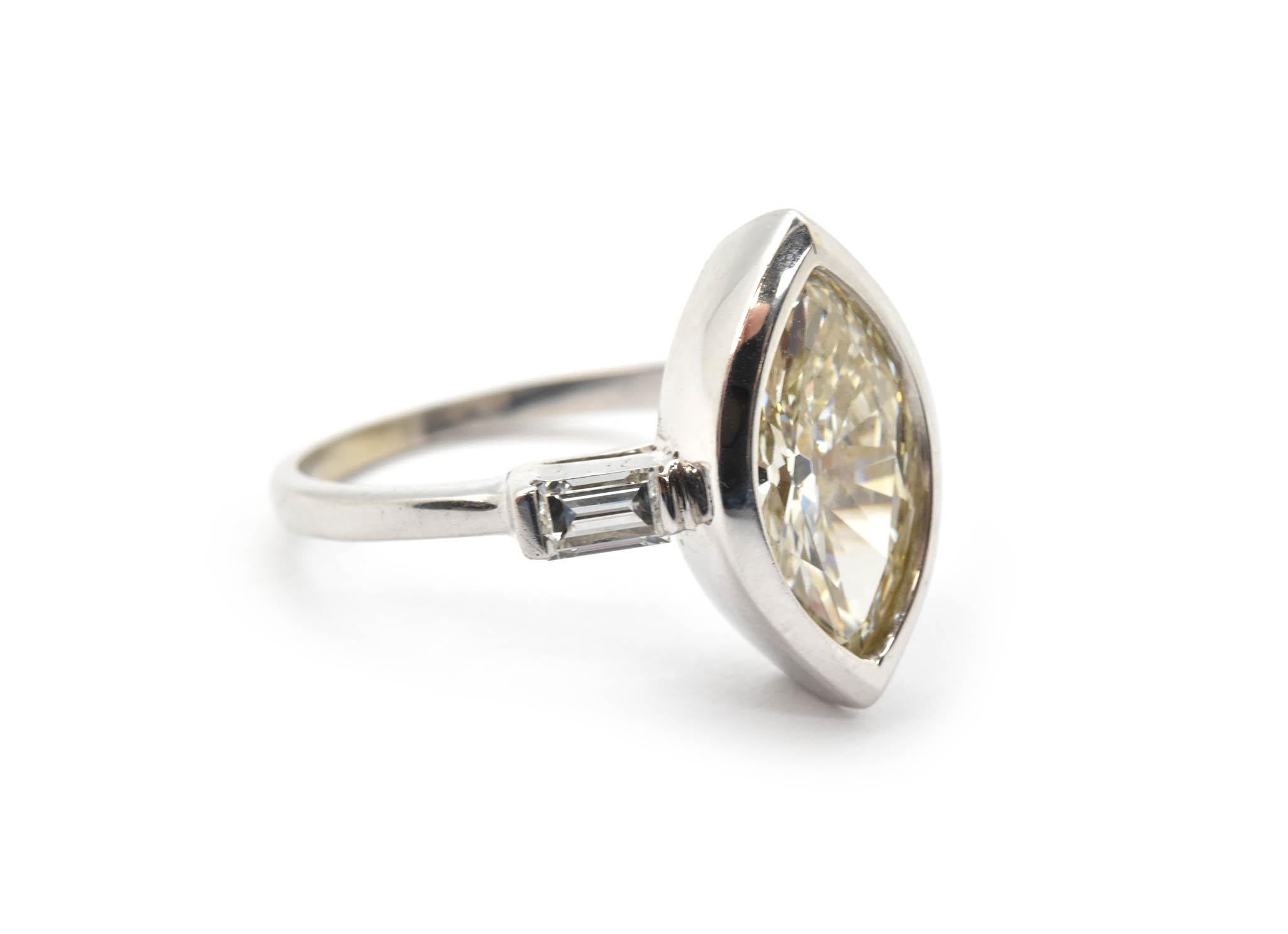 This ring is made in 14k white gold, and it holds a bezel-set 1.90ct marquise diamond. The stone is graded L in color and SI1 in clarity. The shank holds two baguette-cut accent diamonds for an additional weight of 0.24ct. The ring measures 15mm