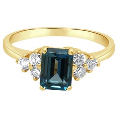 Ring aus 14-karätigem Gelbgold mit einem Smaragdschliff-Blautopas in Krappenfassung und runden Diamanten als Akzente