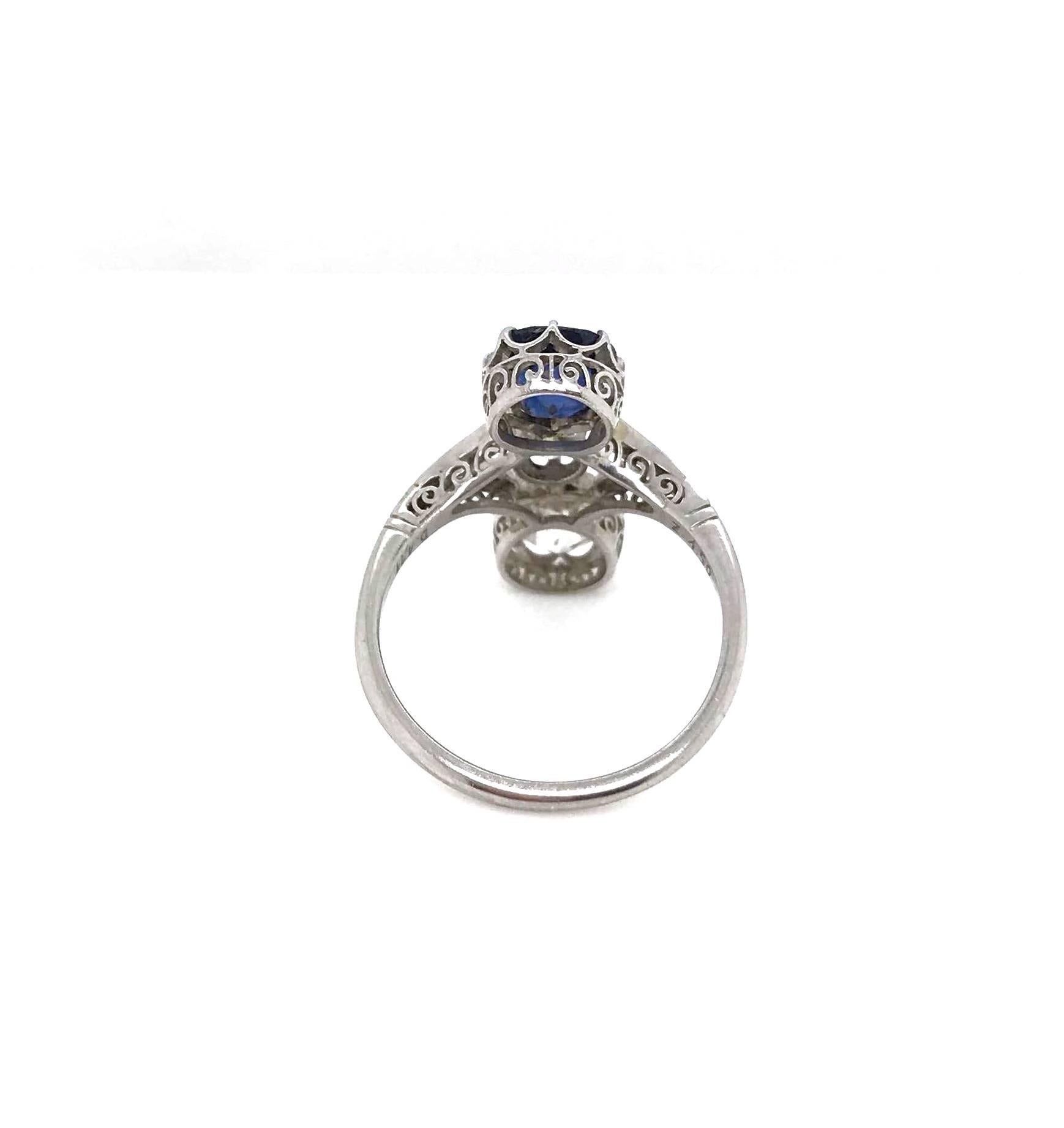 Featuring an eight claw set, deep blue, cushion-cut Sapphire, a four claw set, old cut Diamond and an eight claw set, old cushion cut Diamond set down the finger with split shoulders each grain set with eight old cut diamonds. The split shoulders