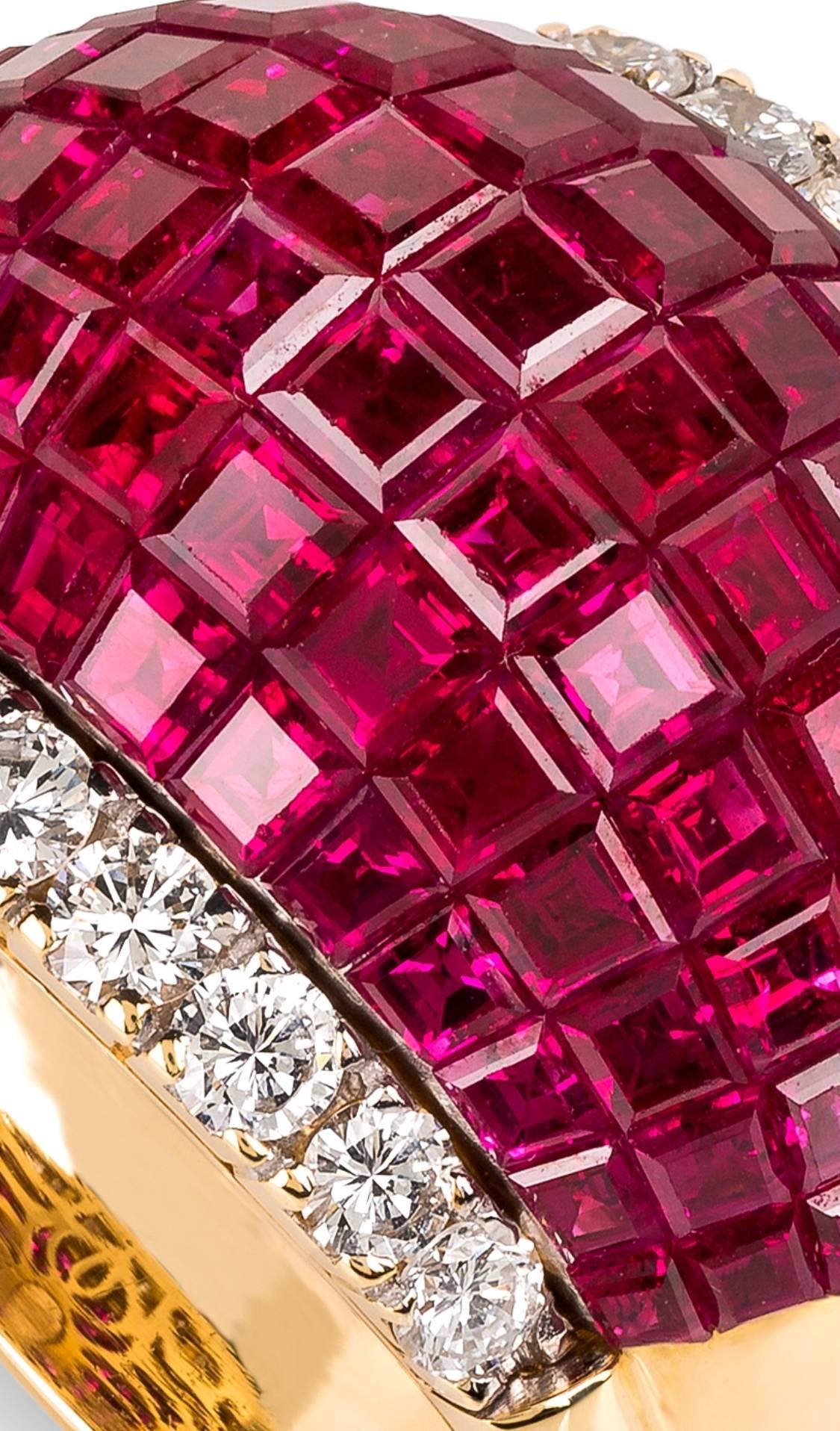 Gold diamond and ruby invisible set ring by Paderzani.
These ring is set with impeccable matched Burmese rubies, the setting invisible to the eyes from the to of the ring. An even flow of gorgeous red around the finger embellished by arow of