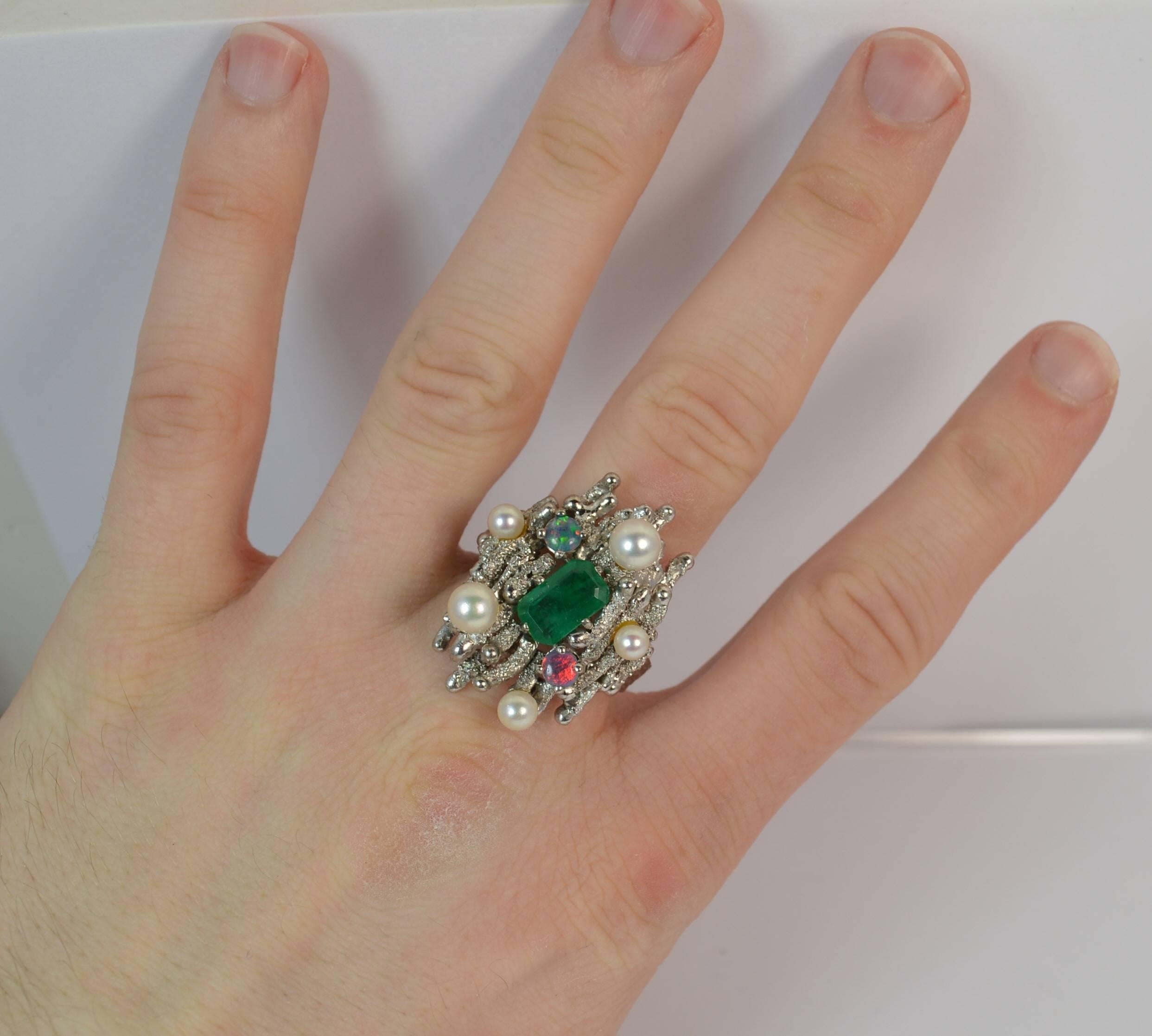 
A very large and impressive retro cluster ring.

​Solid 18 carat white gold example.

​Designed with an emerald cut emerald to the centre, 5.5mm x 9.5mm. Five full pearls and two opal doublets are then surrounding in a scattered design.

​The