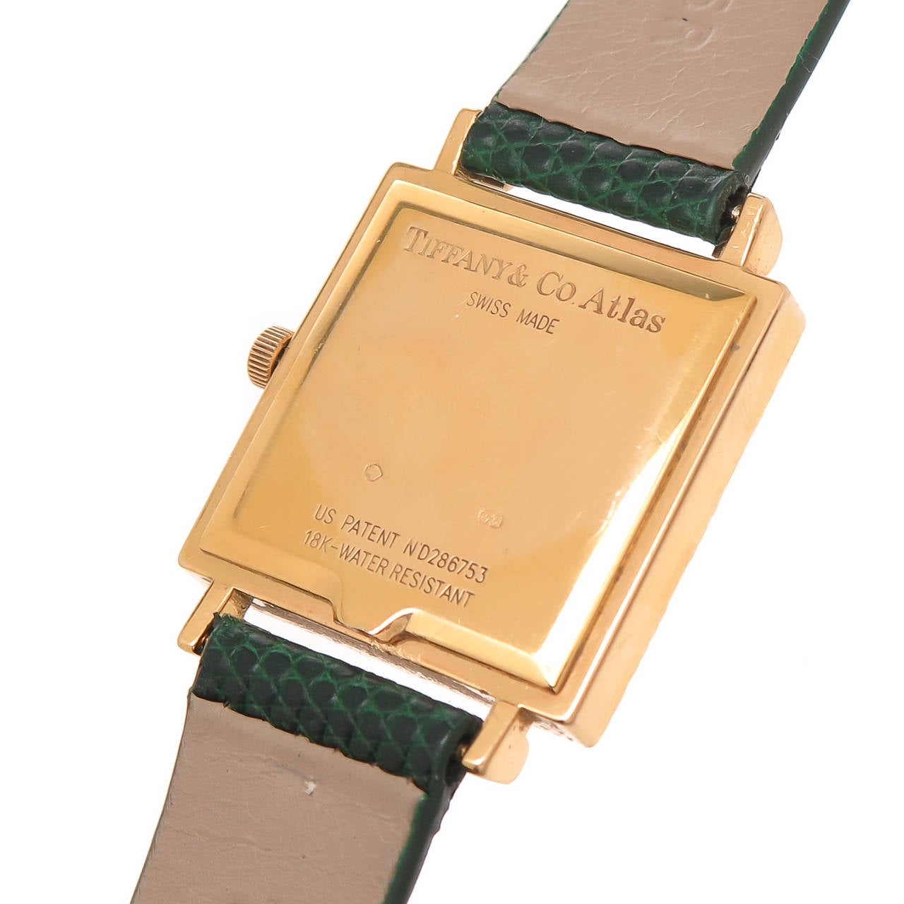 Circa 1990s 18K yellow gold Tiffany & Co. lady's wristwatch from the Atlas collection. Measuring 1 X 1 inch square and 3/16 inch thick with raised Roman numerals around the bezel, quartz movement and gold dial. Original green lizard strap with gold