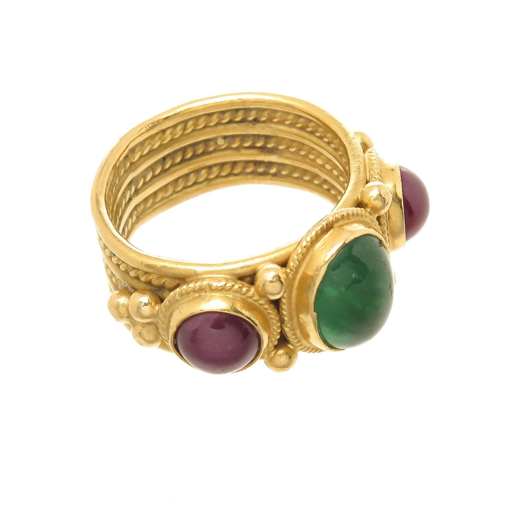 Circa 1990s Lalaounis 18k Yellow Gold band ring in the Greek Revival style, typical of Lalaounis jewelry, measuring 5/16 inch wide, the top is centrally set with an Oval Cabochon Emerald of approximately 2 Carats and further set on either side with