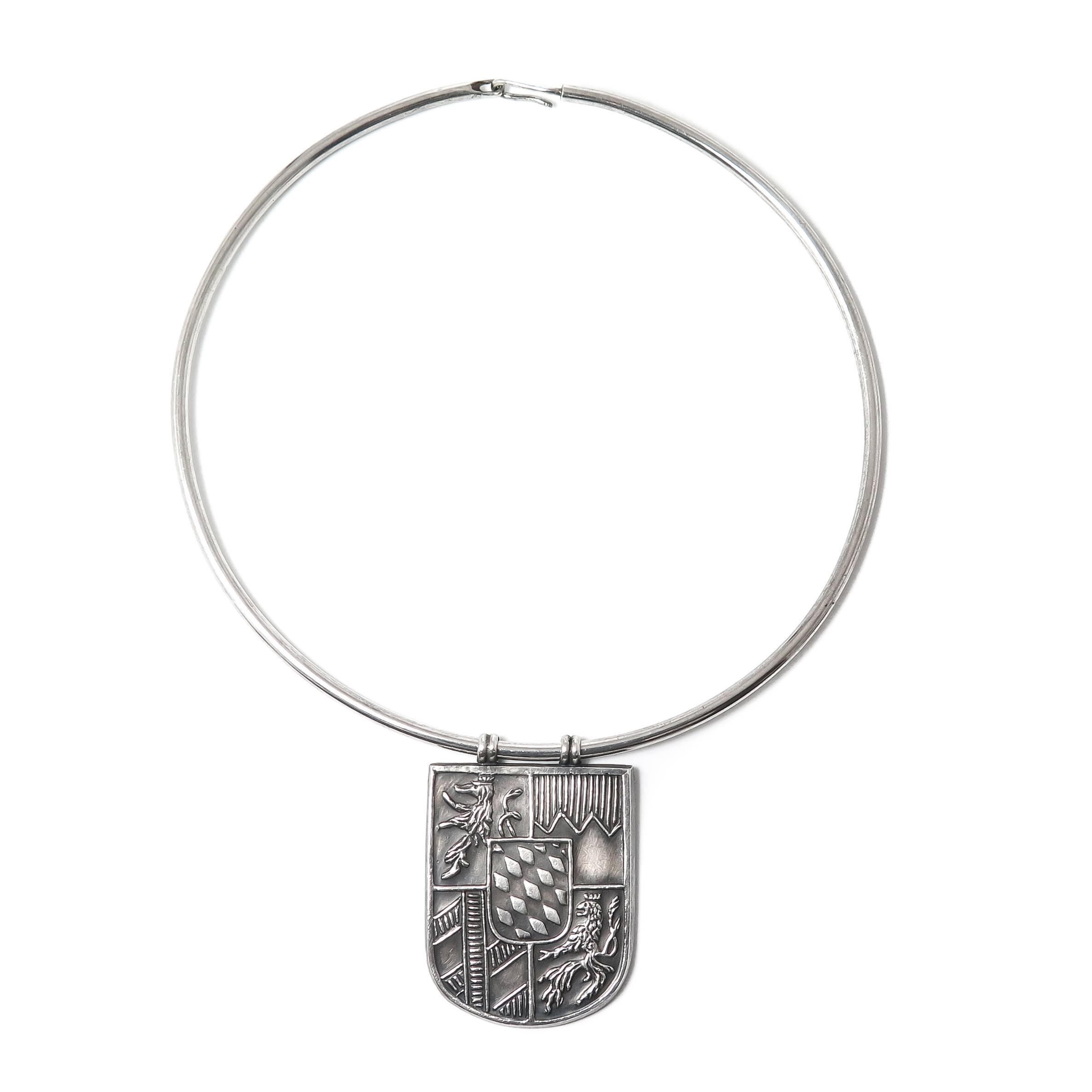 Circa 1970s Lalaounis Sterling Silver Shield pendant with Crest measuring 2 X 1 3/8 inch and suspended from a 3 MM thick Torque  style necklace measuring approximately 16 inch.
