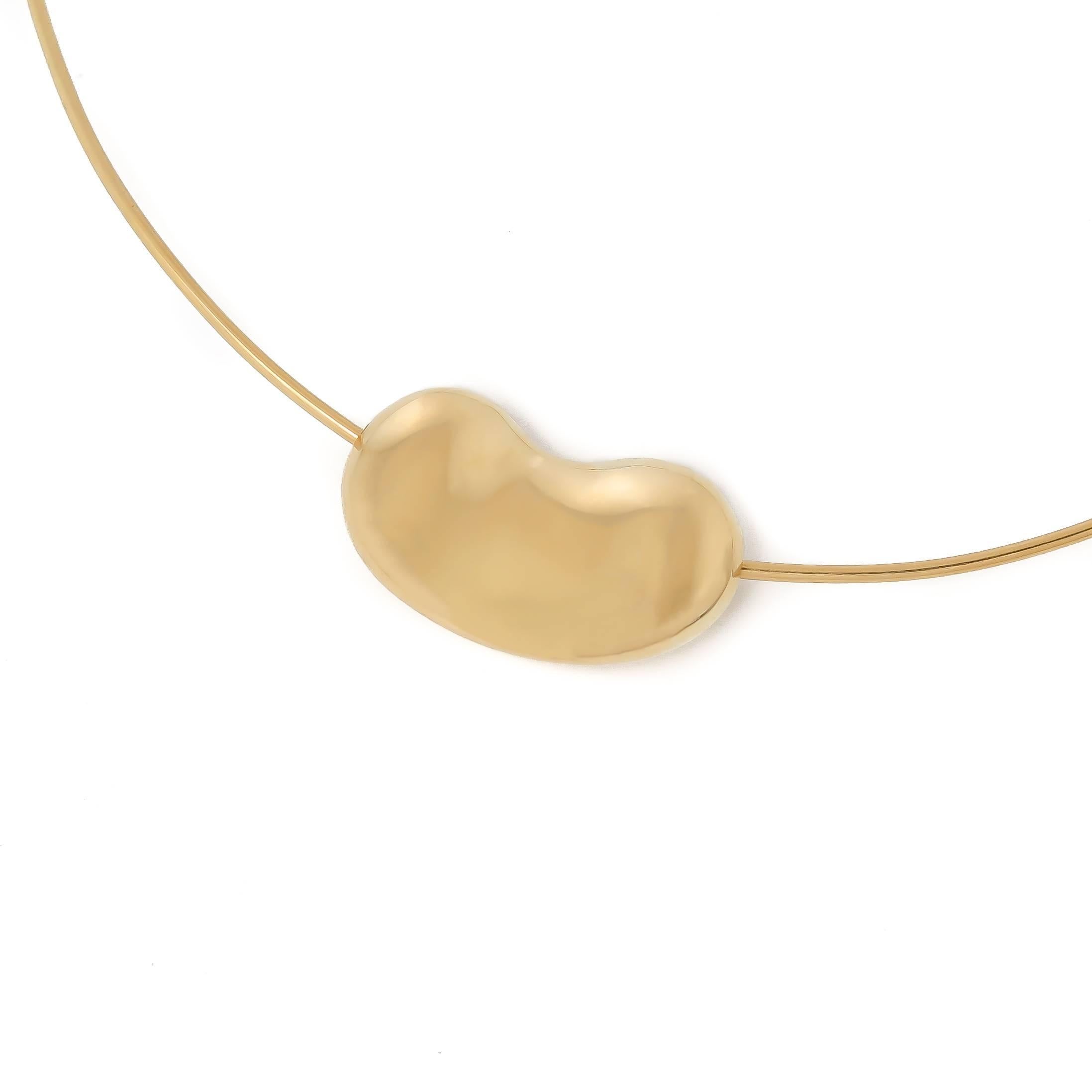 Circa 1980 Elsa Peretti for Tiffany & Company 18K yellow Gold Bean Necklace, measuring 1 1/8 X 5/8 inch and suspended from a Torque Wire measuring 16 inch. The bean floats freely on the wire for movement. 