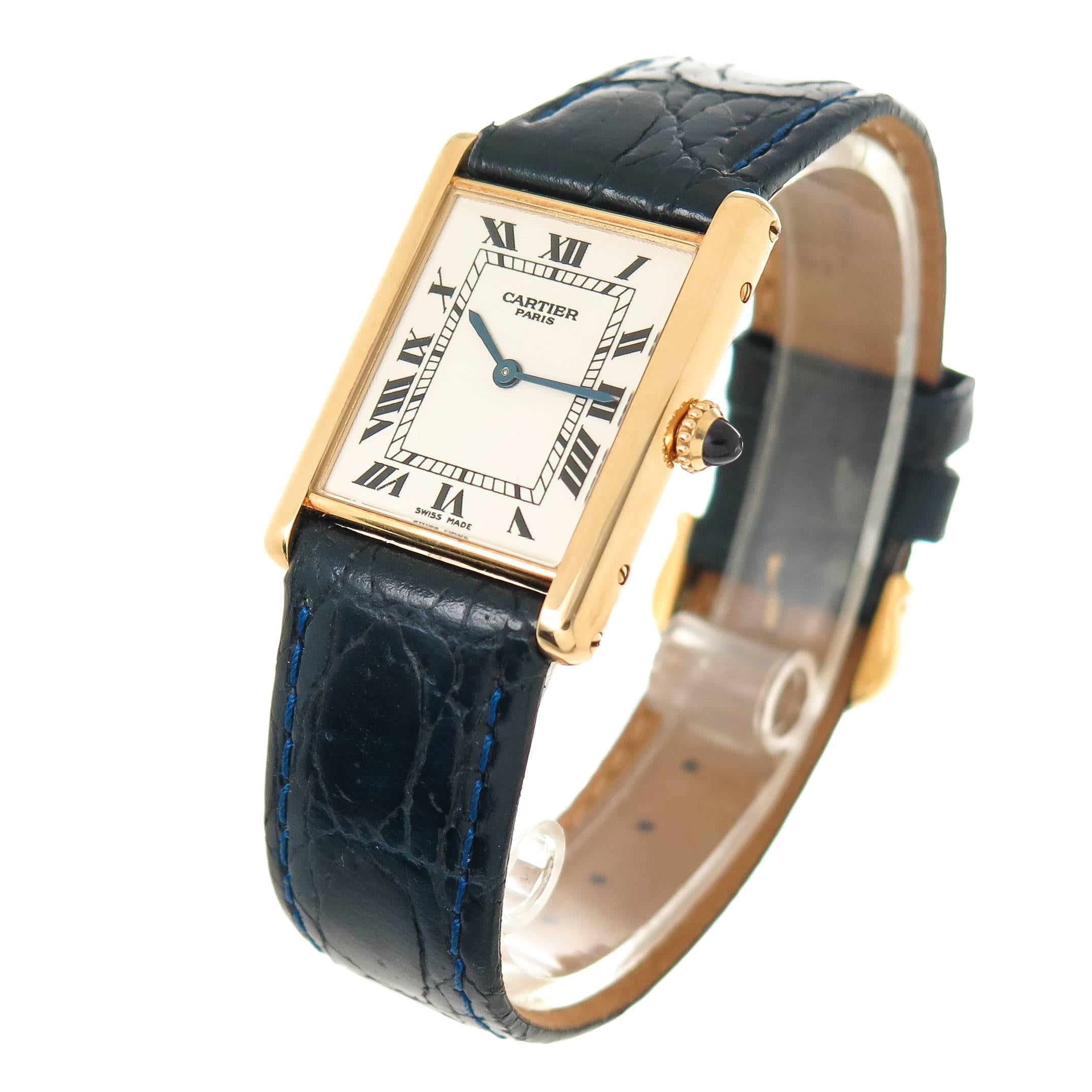Circa 2000 Cartier classic 18K yellow Gold Tank watch. 30 X 23 MM Water Resistant case. Mechanical winding movement. Engine turned Silvered Dial with Black Roman Numerals, sapphire Crown. New Hadley Roma Dark Blue Textured strap with Gold Plate